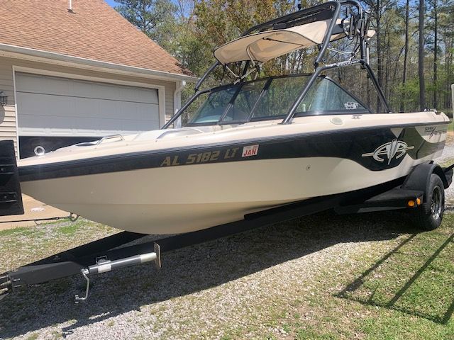 2001 Correct Craft Super Air Nautique boat on trailer near garage.