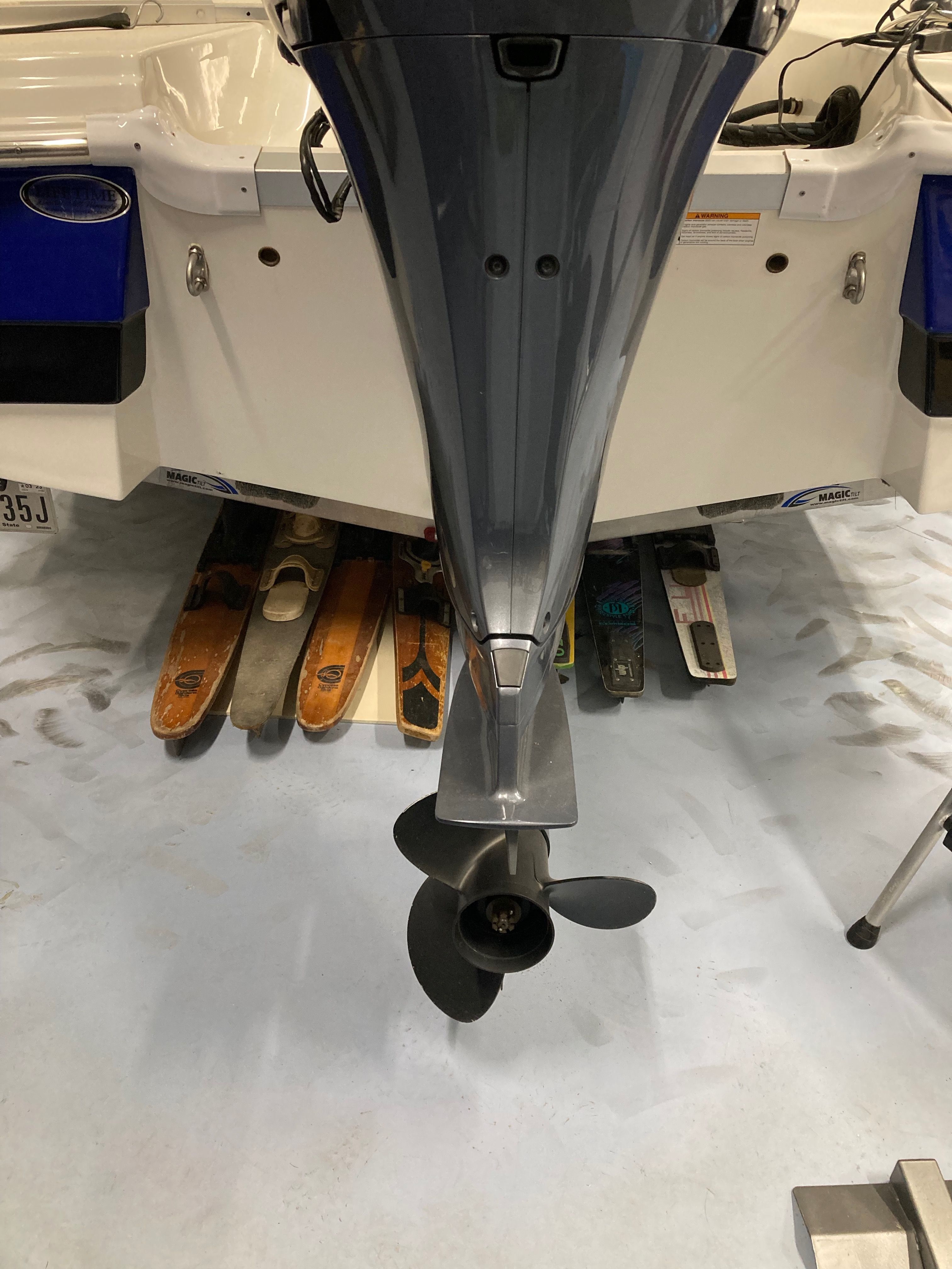 Rear view of a boat with an outboard motor and water skis underneath.