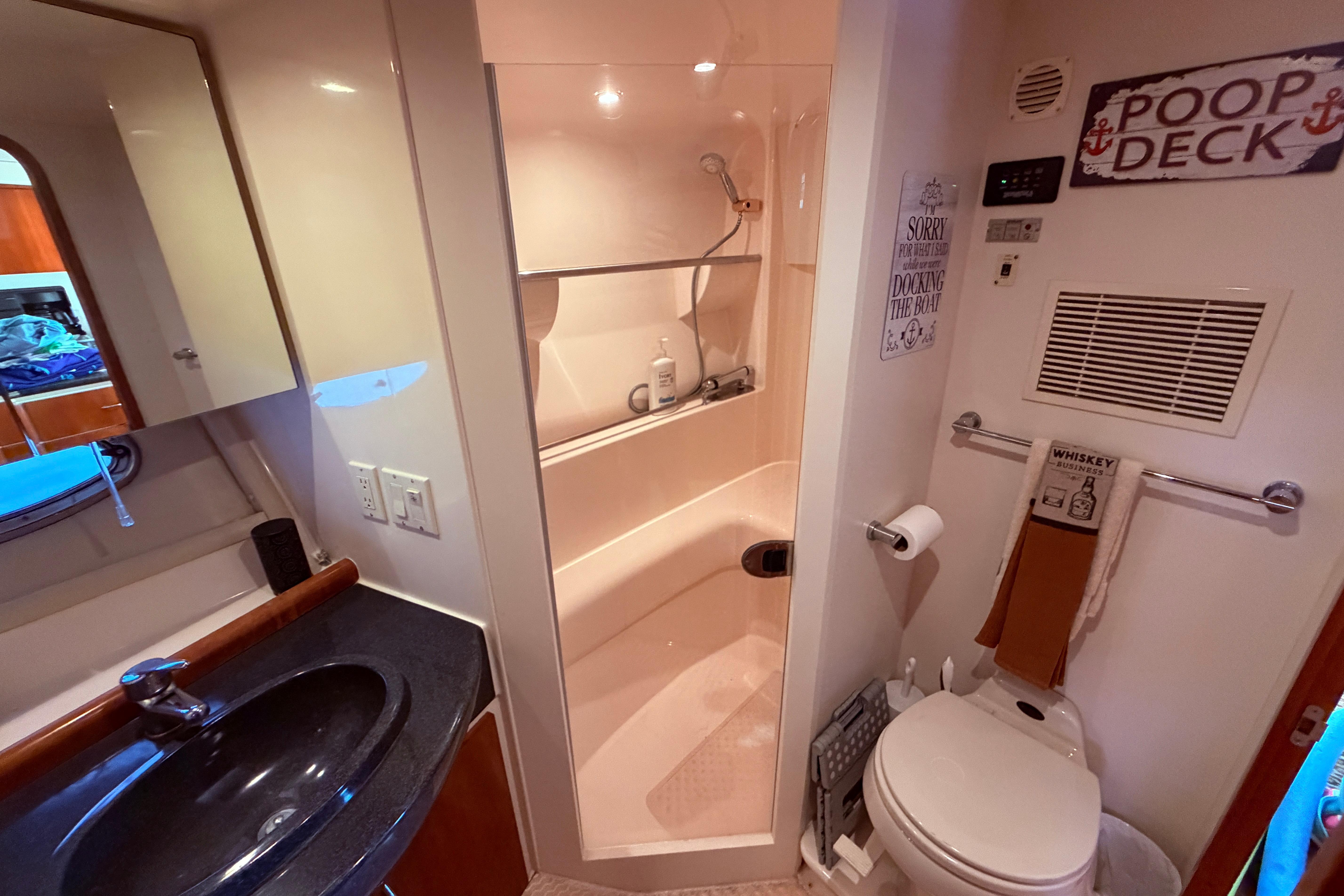 Bathroom interior of 2003 Carver 350 Mariner yacht, featuring shower, sink, and humorous decor.