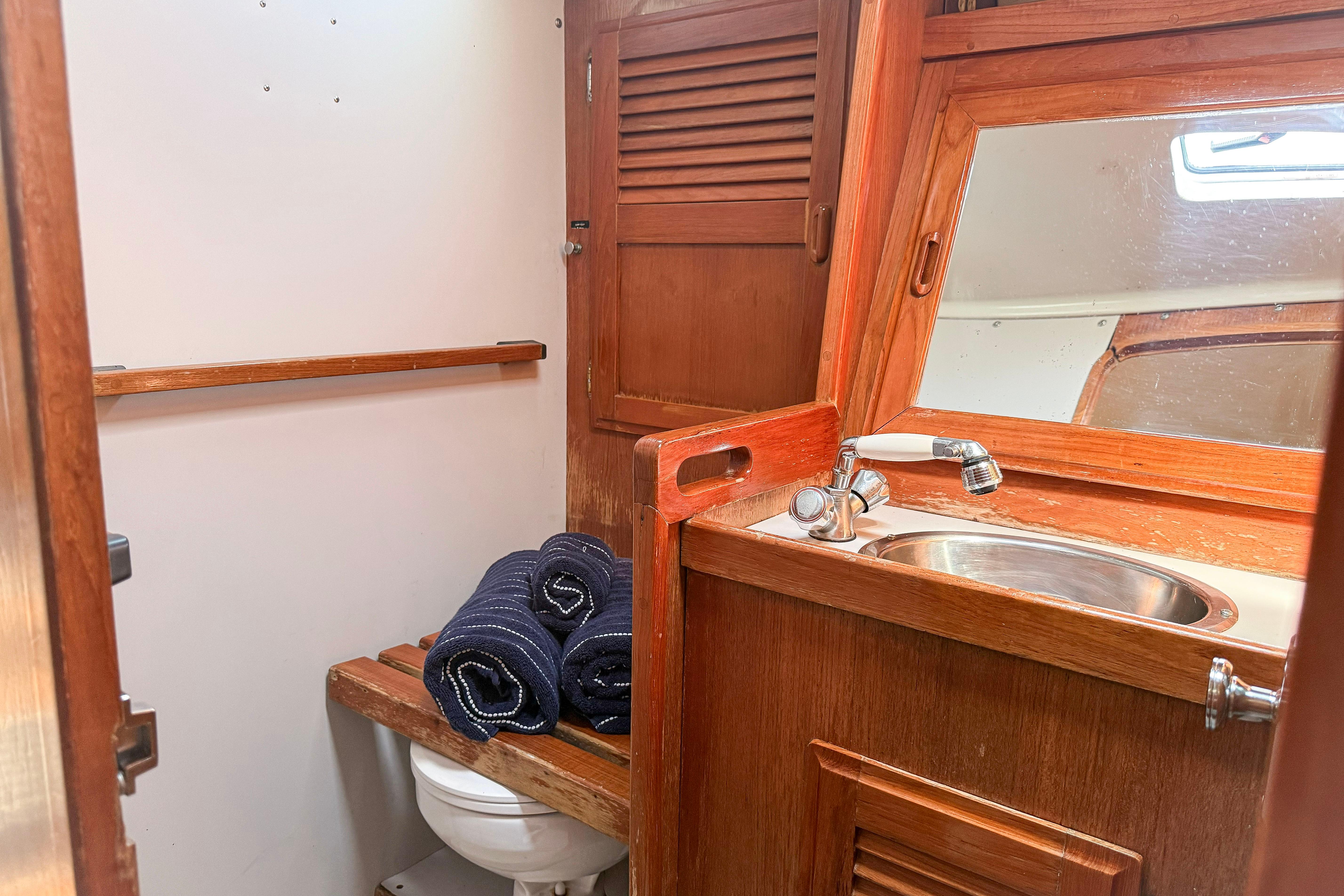 1988 Oday 40 yacht bathroom with wooden cabinetry, sink, and rolled towels.