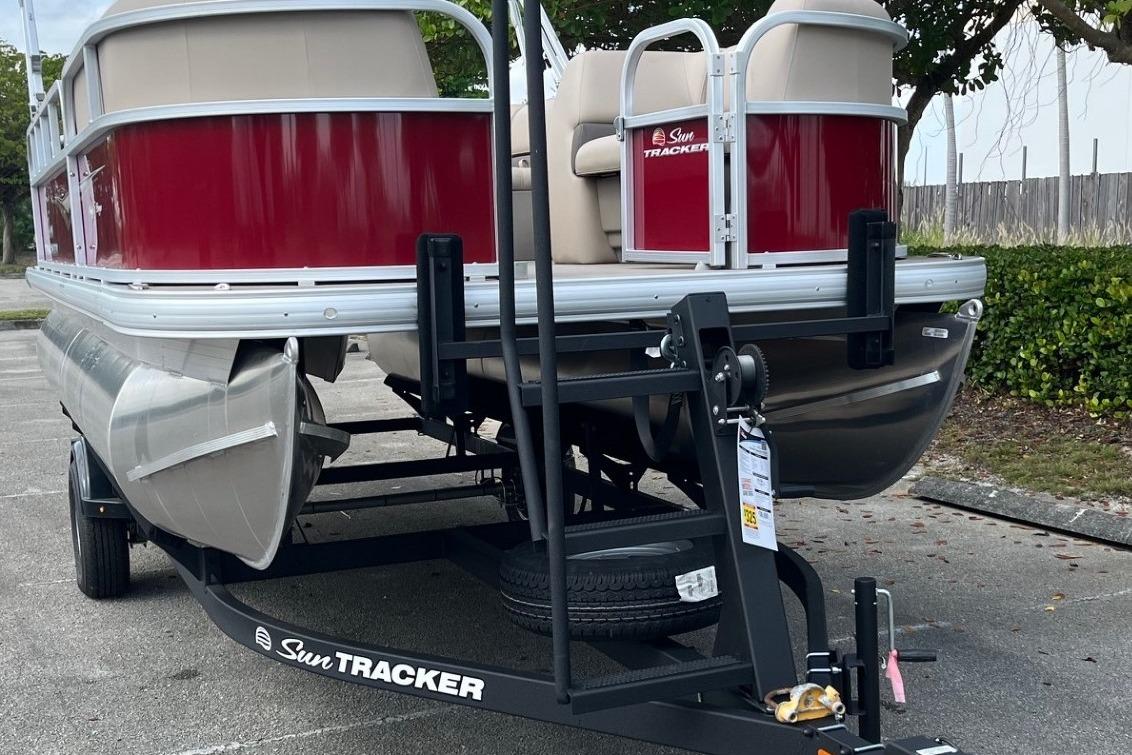 2025 Sun Tracker Party Barge 18 DLX pontoon boat on trailer, parked outdoors.