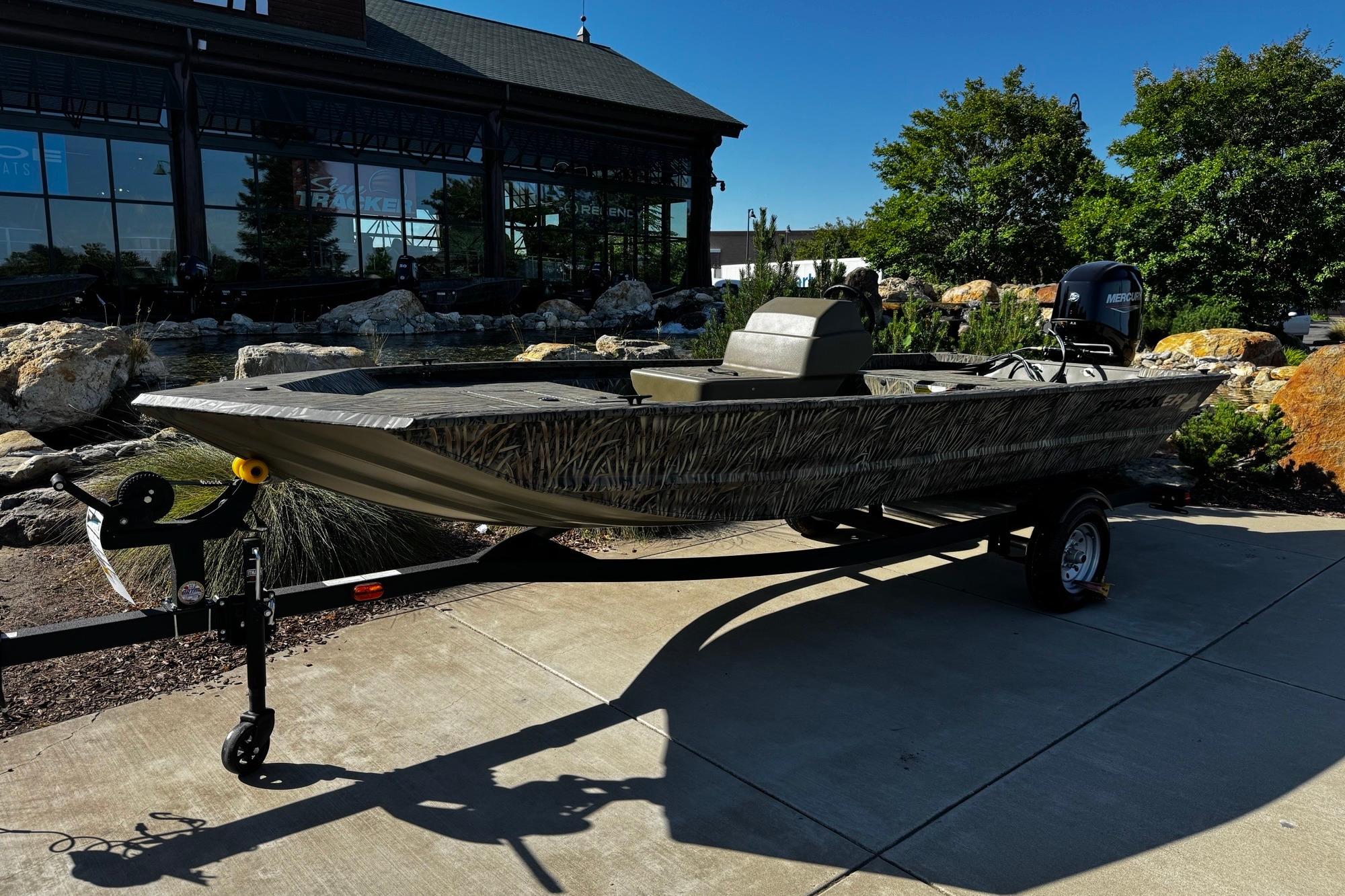 2026 Tracker Grizzly 1648 SC boat on trailer, parked outdoors near a building.