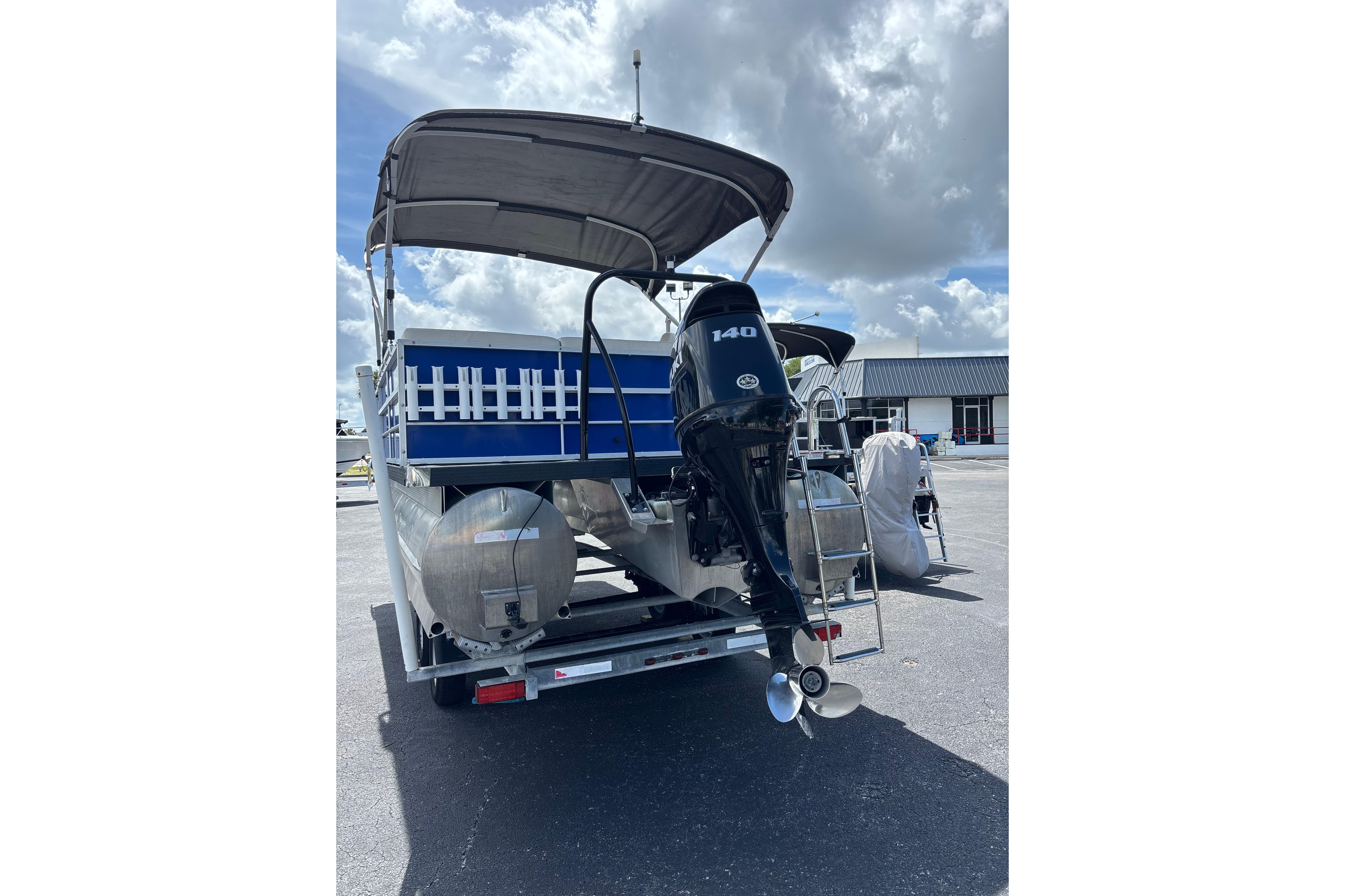 2022 Lexington 323 pontoon boat with outboard motor, parked under cloudy sky.