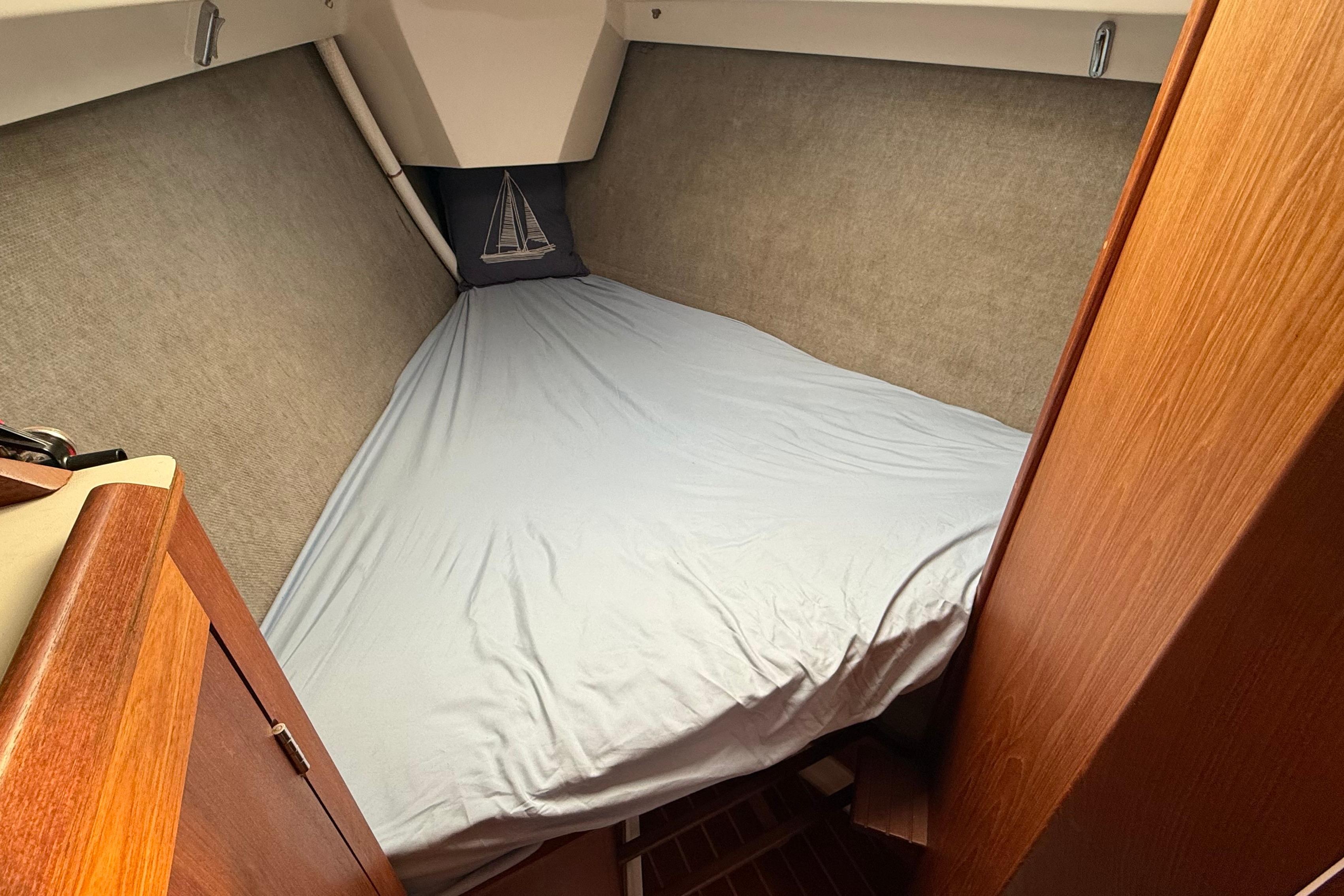 Cozy cabin interior of 1984 Hunter 31 sailboat with blue bedding and wooden accents.