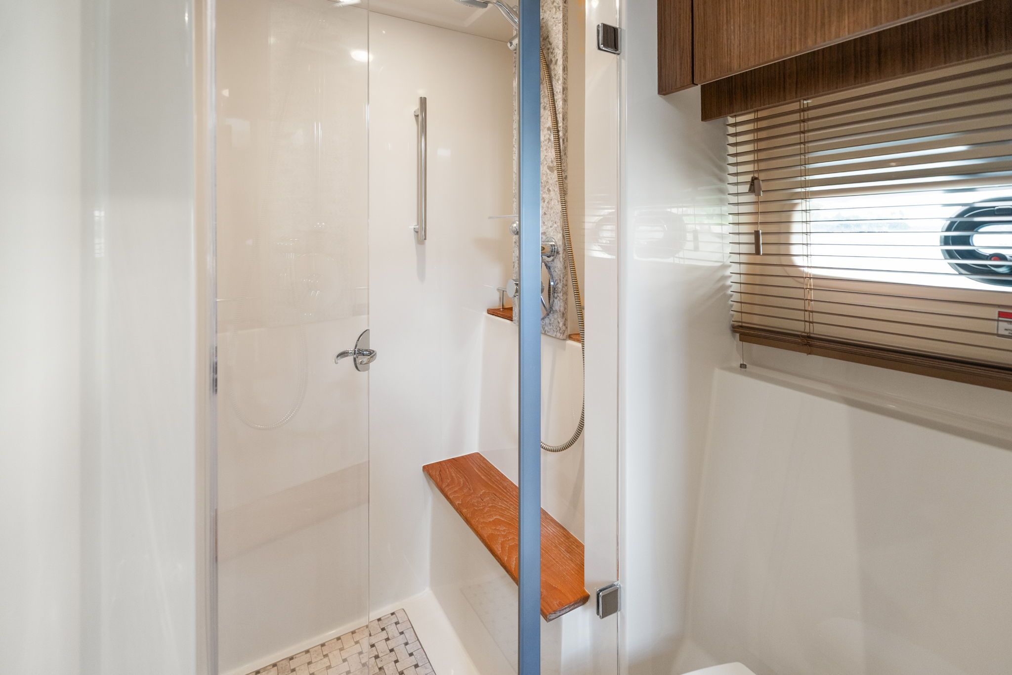 The 2017 Sea Ray Sundancer 510 shower features a glass door and wooden accents.