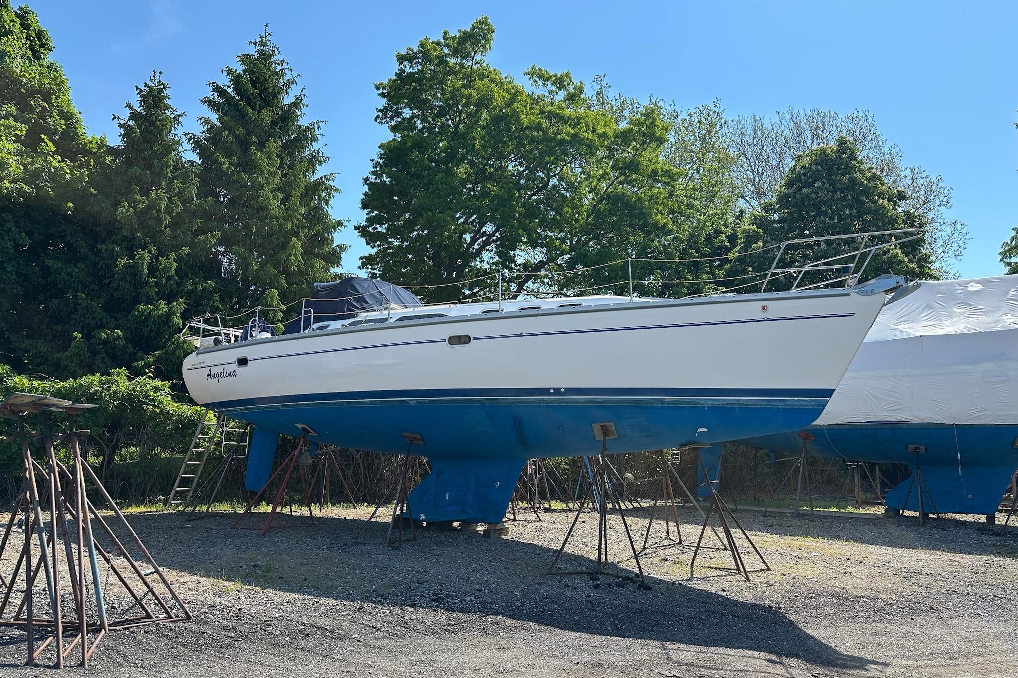 2002 Catalina 400 MkII sailboat on stands, surrounded by trees and clear sky.