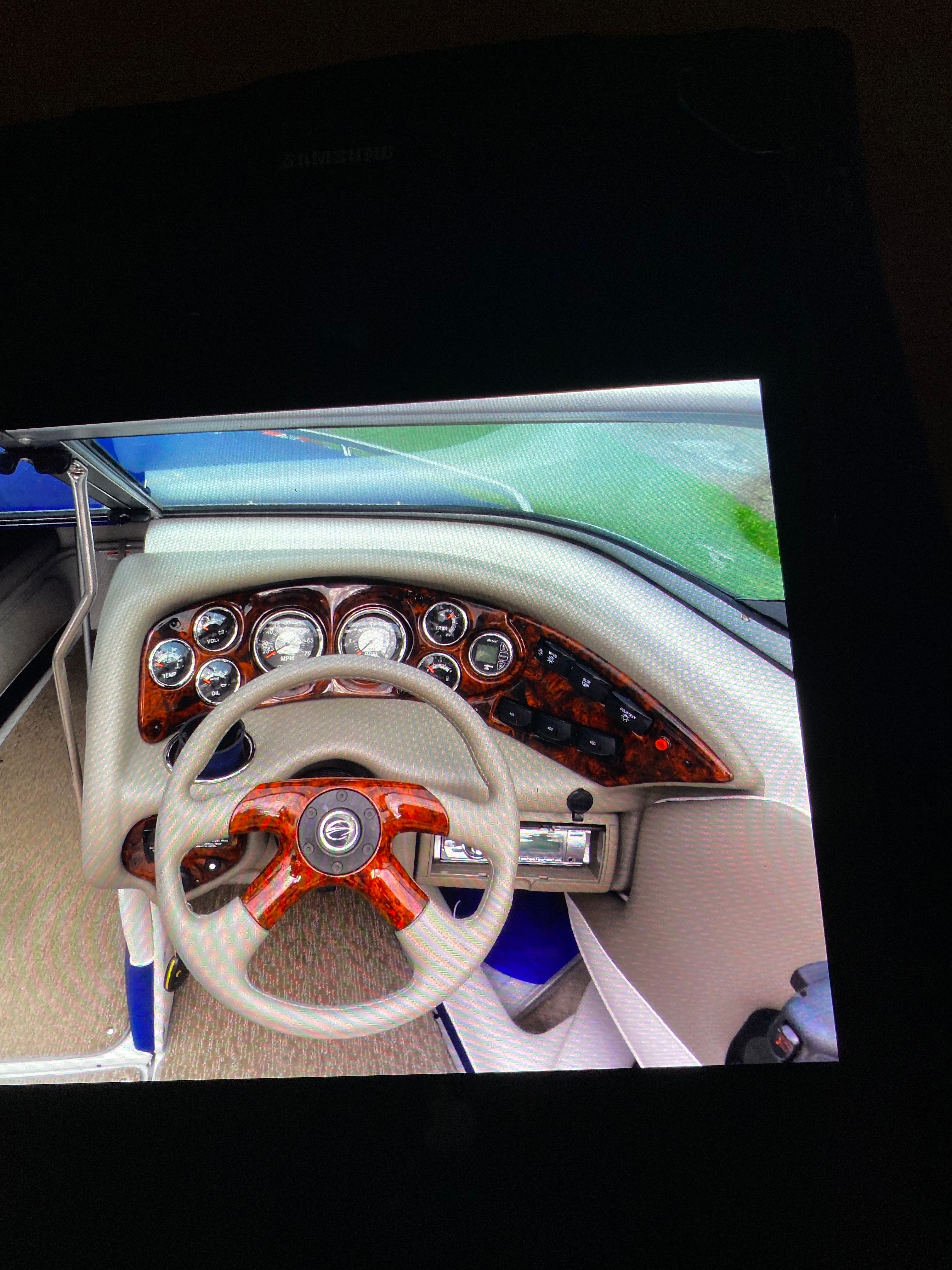 The image shows the dashboard of a Crownline 21 bow rider boat with wood trim.