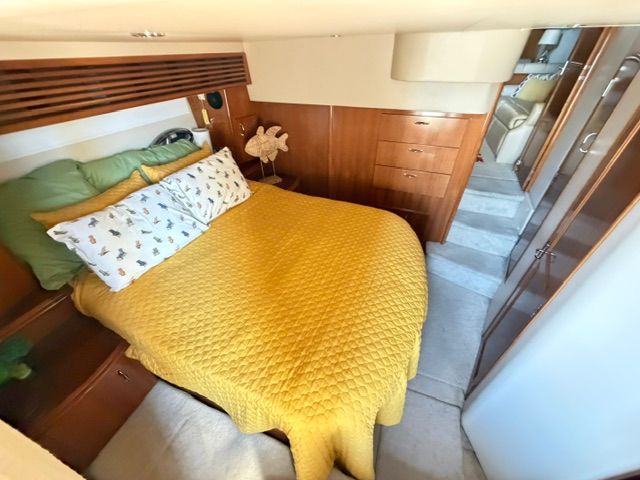 Cabin of the 2005 Carver 44 Cockpit Motor Yacht with a cozy bed and wooden furnishings.