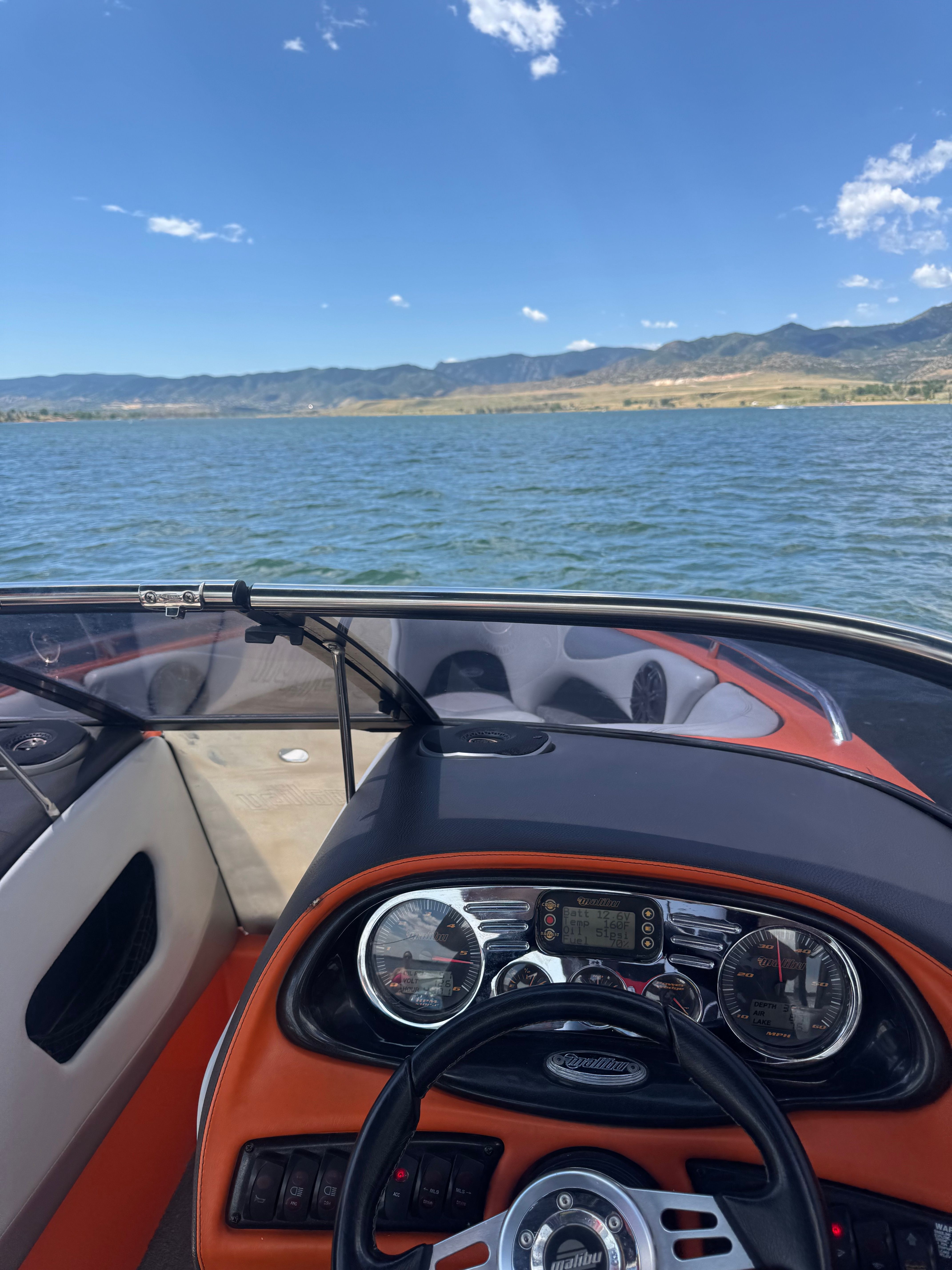 The cockpit of a 2006 Malibu Wakesetter 23 LSV on a lake with mountain views.