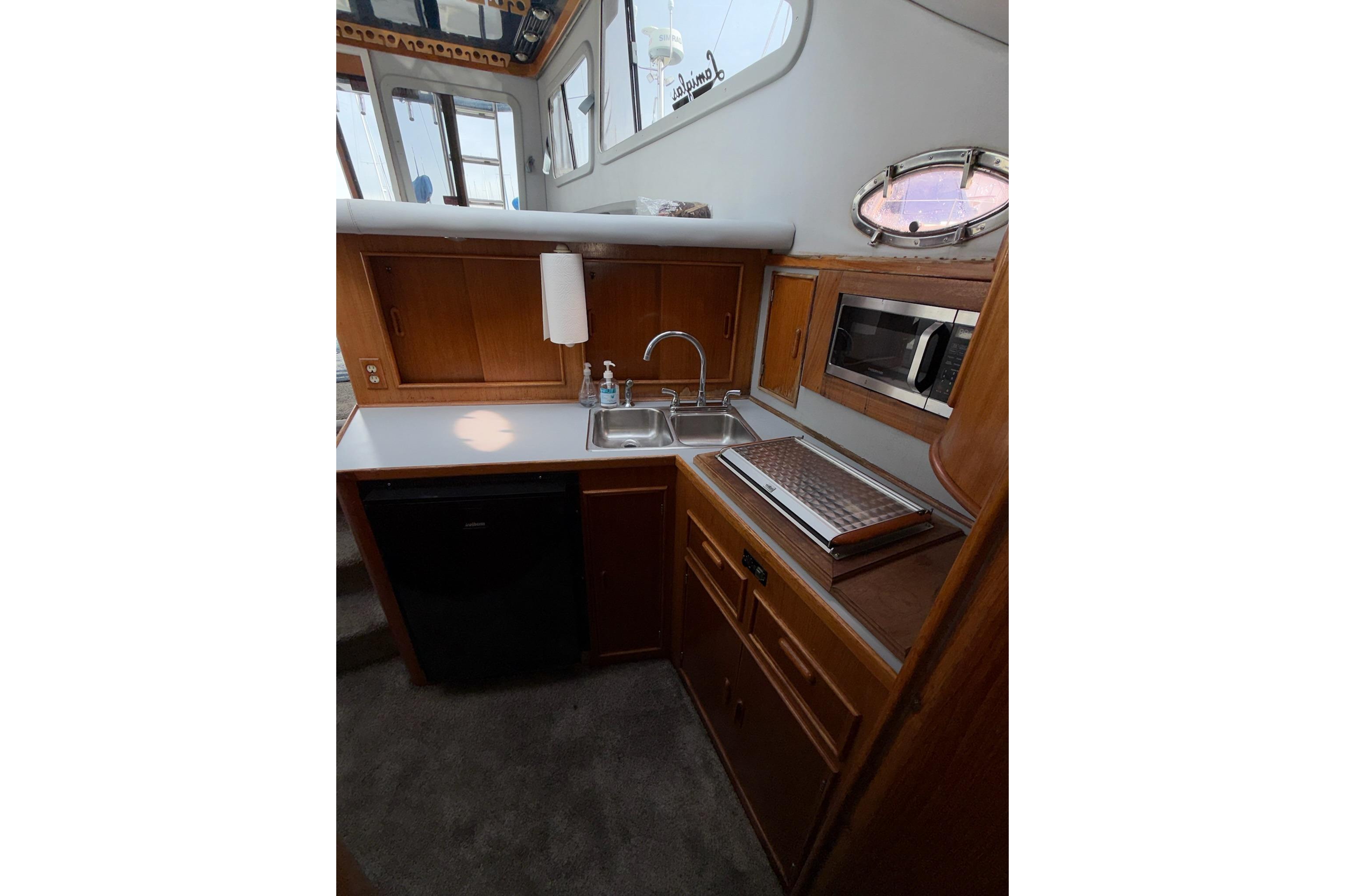 1990 Mediterranean Sport Fish boat kitchen with wooden cabinets, sink, and microwave.