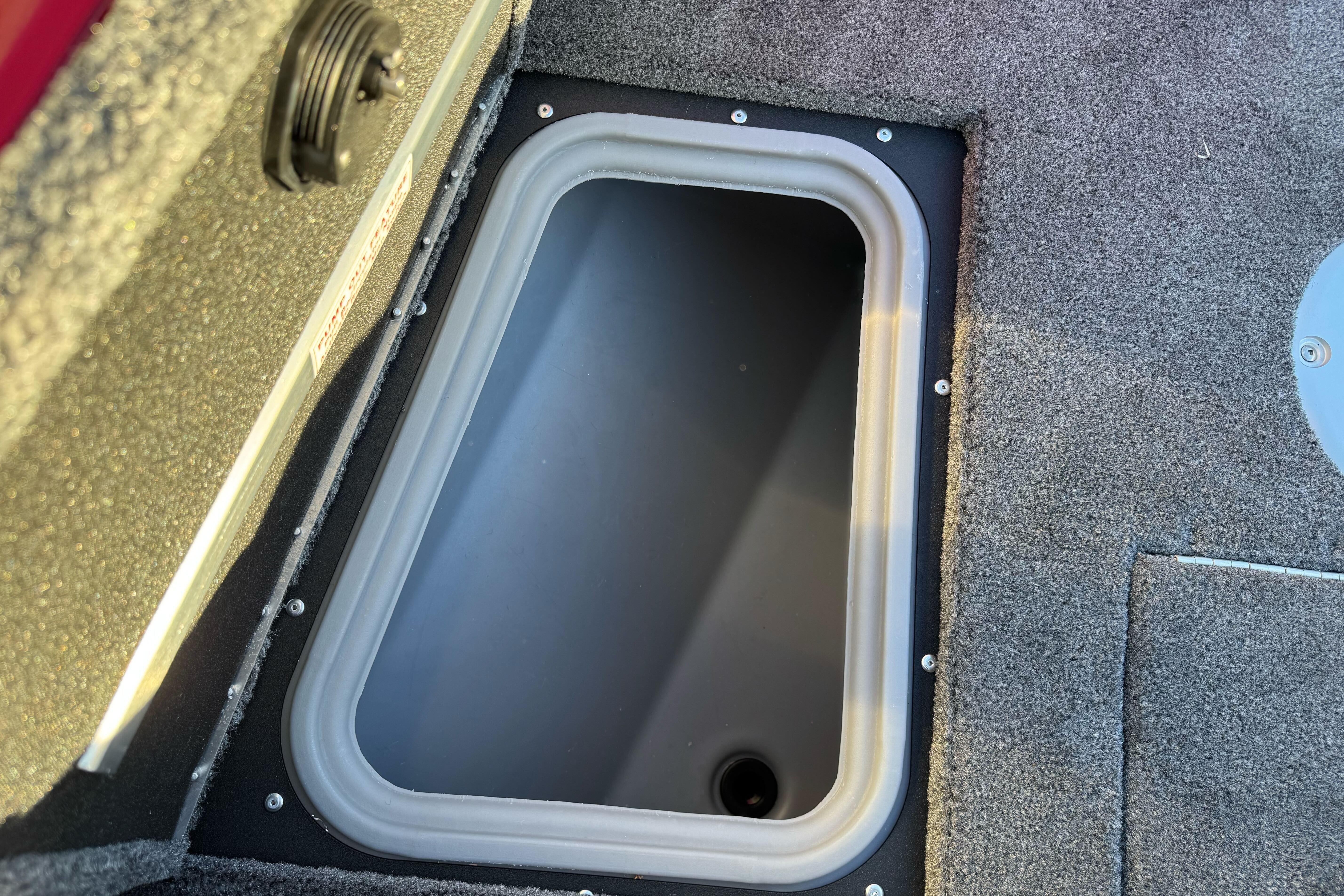 Storage compartment in 2026 Tracker Targa V-18 WT boat, featuring carpeted interior.
