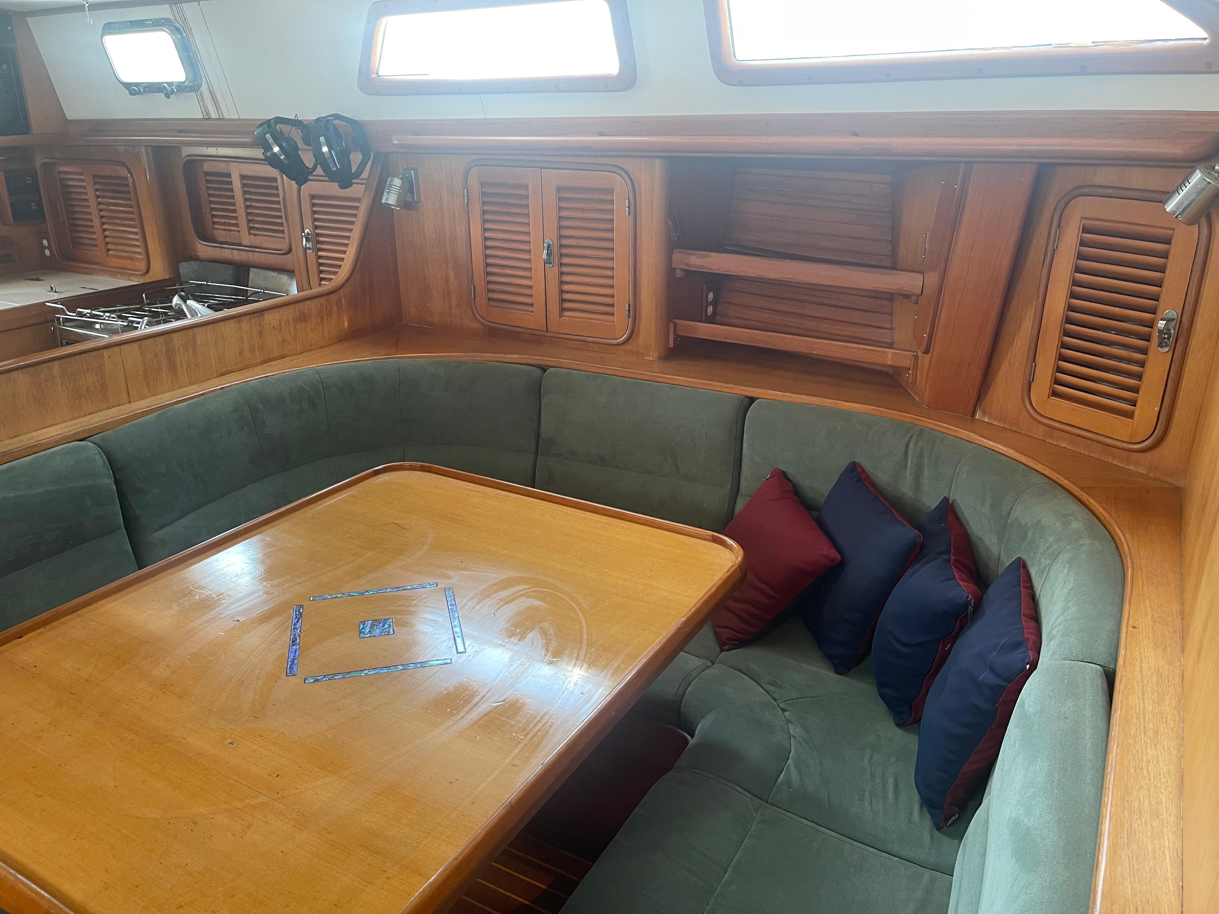 Interior of 1995 Passport 47 AC Plan B sailboat with dining area and wooden cabinetry.