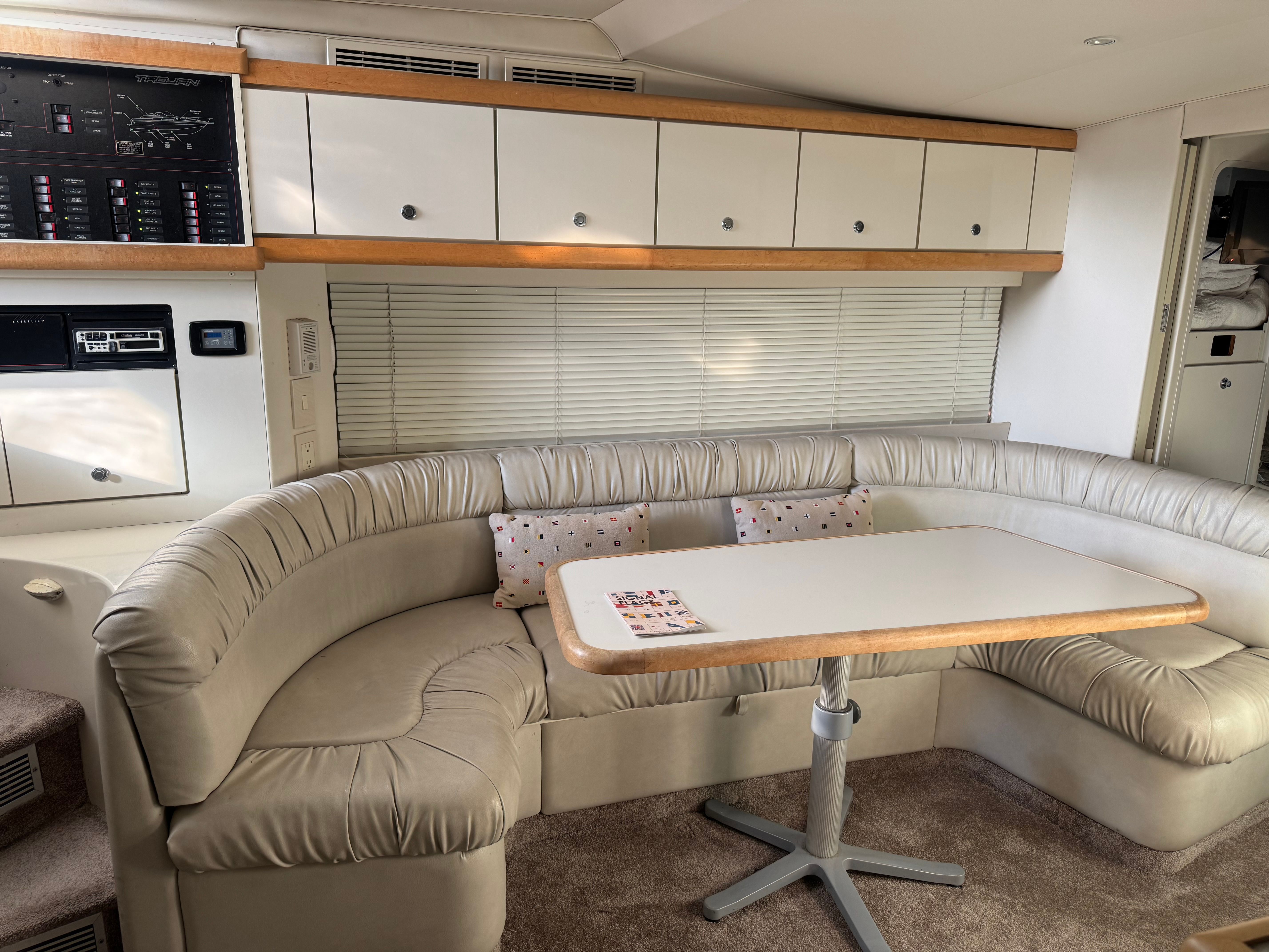 Interior of a 1995 Trojan 390x with beige curved sofa and table.