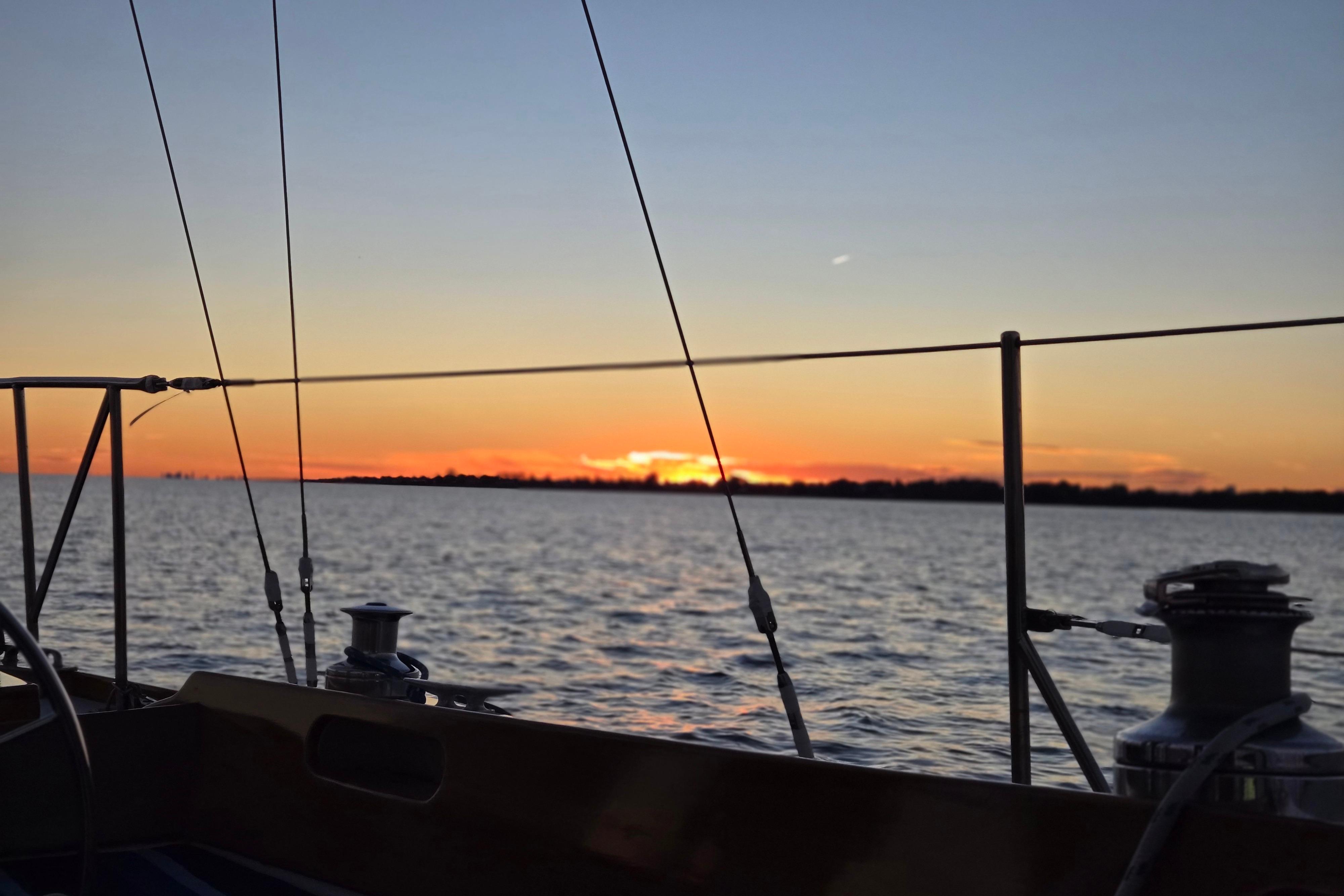Sailing on a 1970 Hinckley Bermuda 40 at sunset over calm waters.