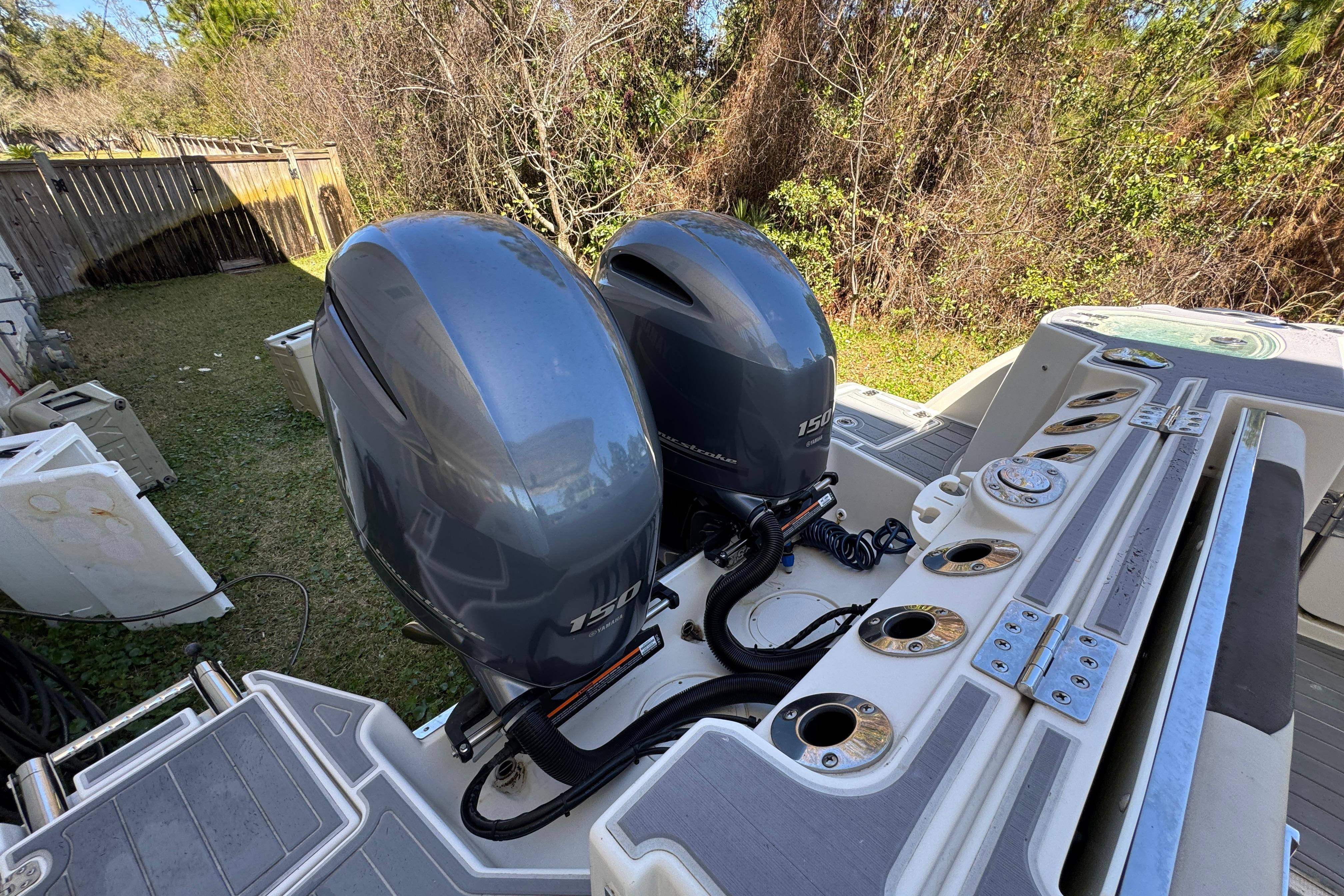 Twin outboard motors on a 2022 Sailfish 276 DC boat, parked in a grassy yard.