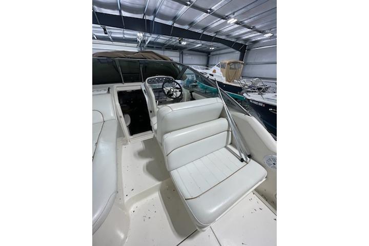 1998 Searay 270 Sundancer boat interior with white seating and steering wheel in a storage facility.