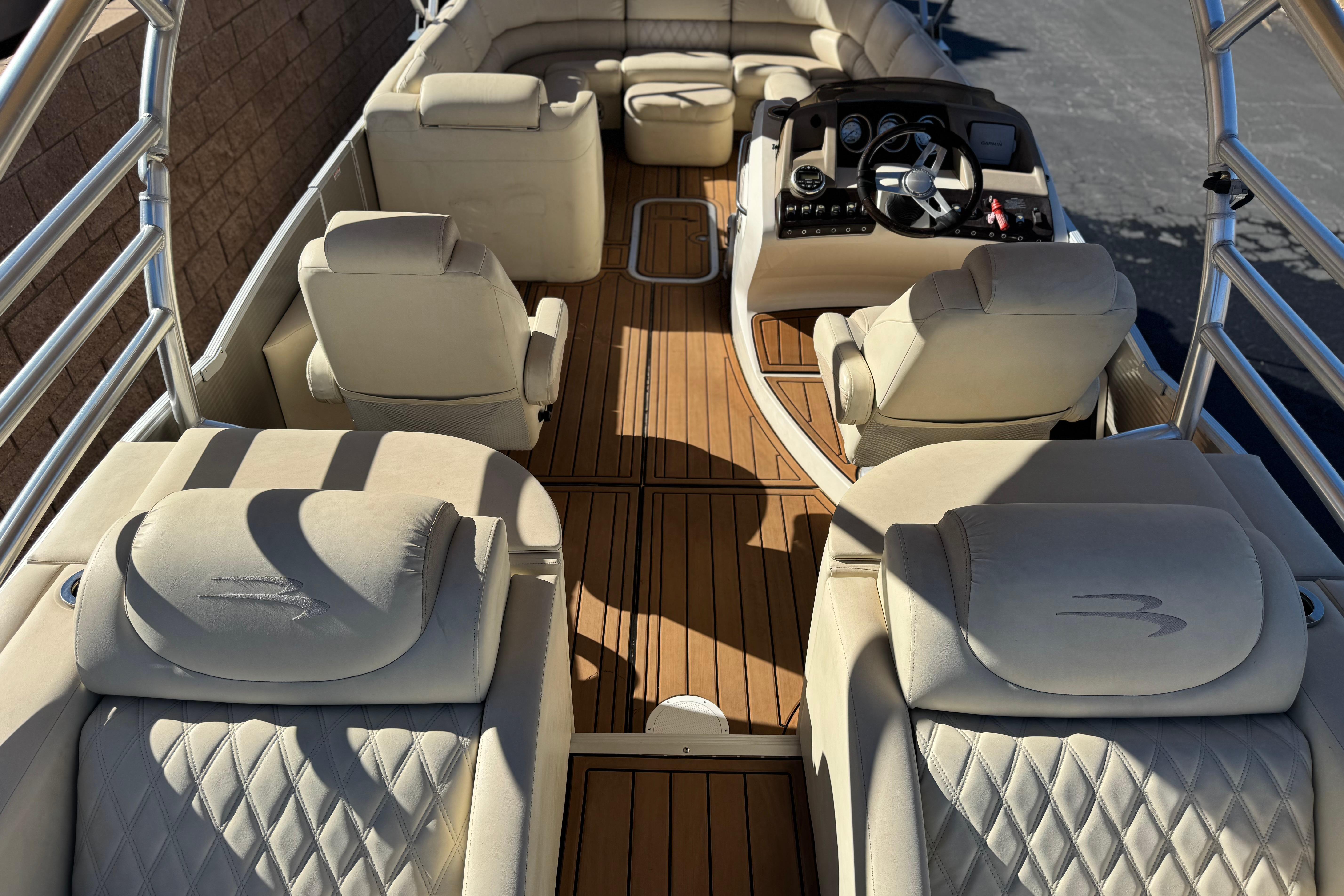 Luxurious interior of a 2013 Bennington 2575QCW I/O boat with plush seating and wood flooring.