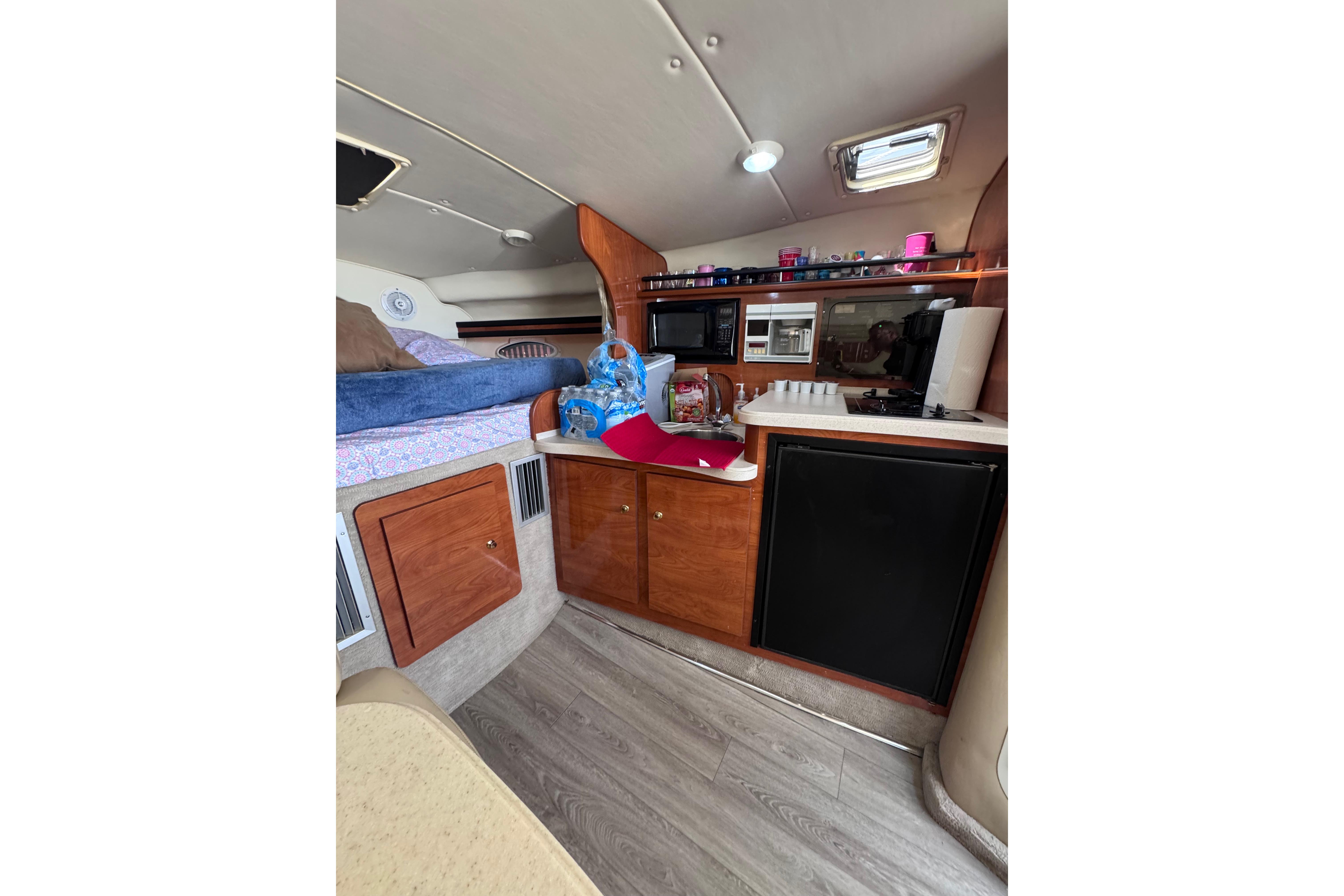 Interior of 2003 Rinker Fiesta Vee 312 boat with kitchenette and sleeping area.