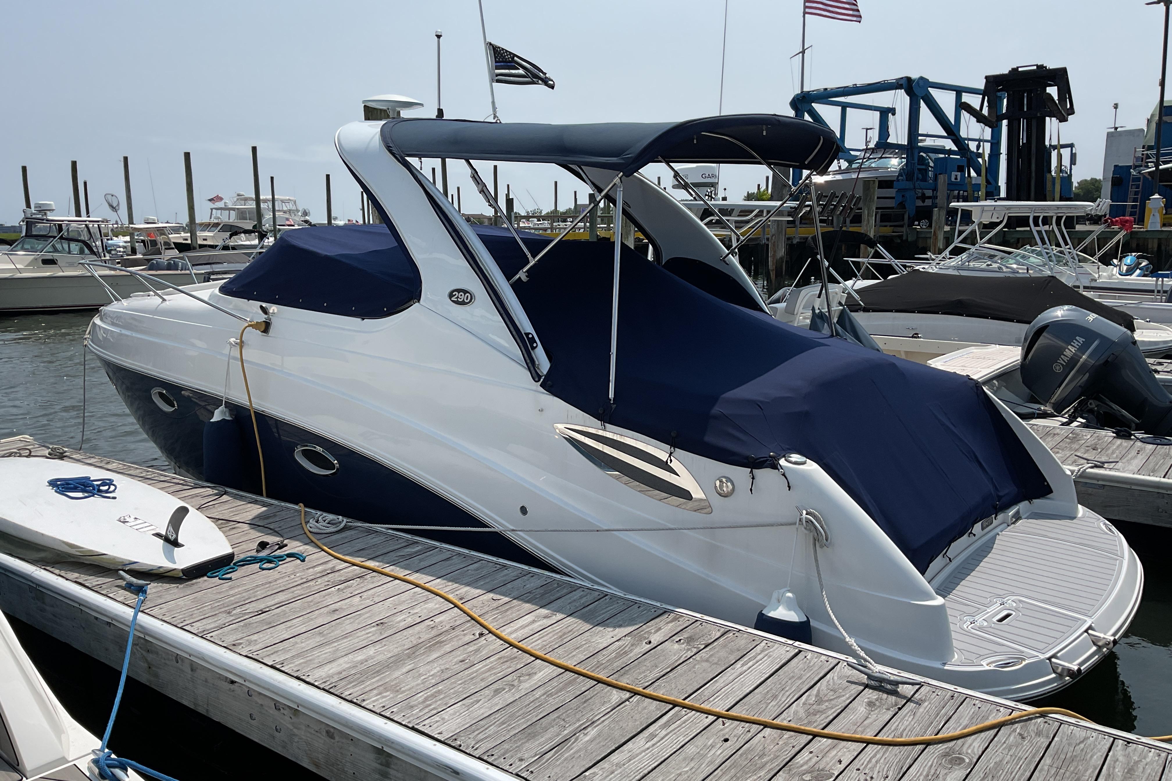 2013 Rinker 290 Express Cruiser docked at a marina with blue cover.