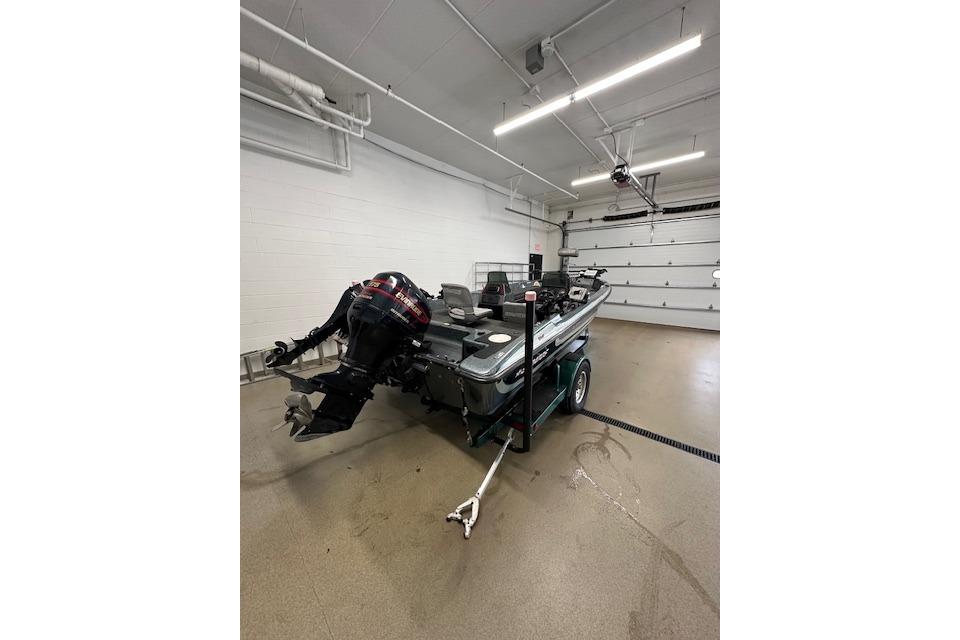 1999 Stratos 219 CF boat in garage, featuring outboard motor and trailer.