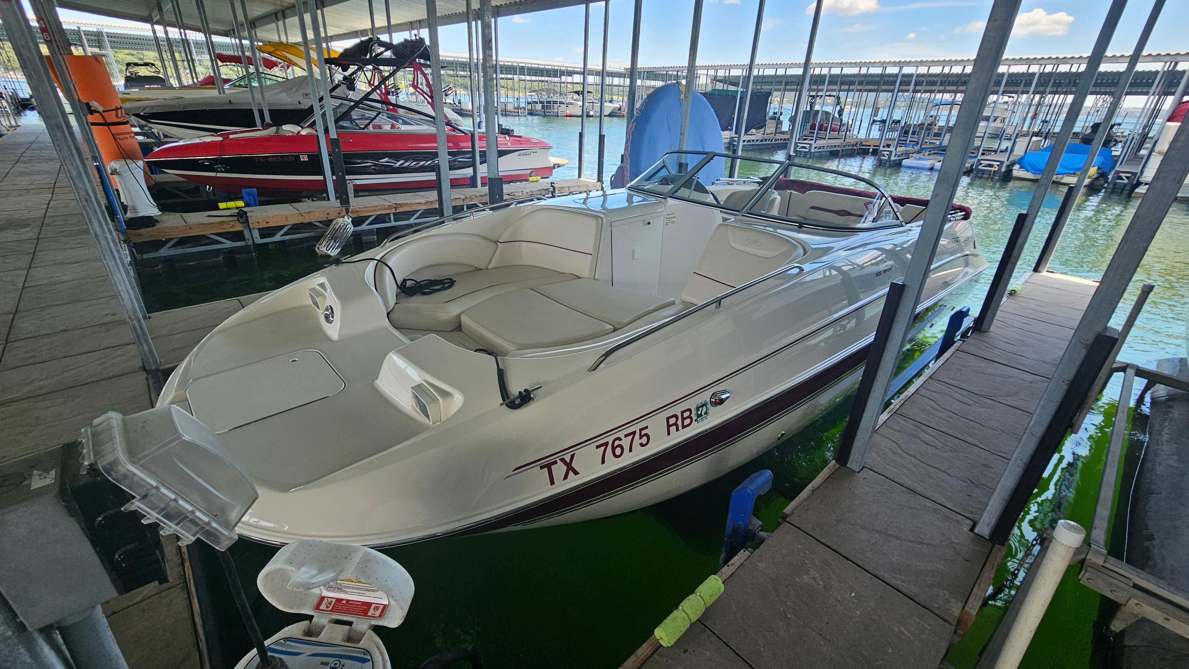 A white 2002 Monterey 220 Explorer Sport boat is docked in a covered marina.