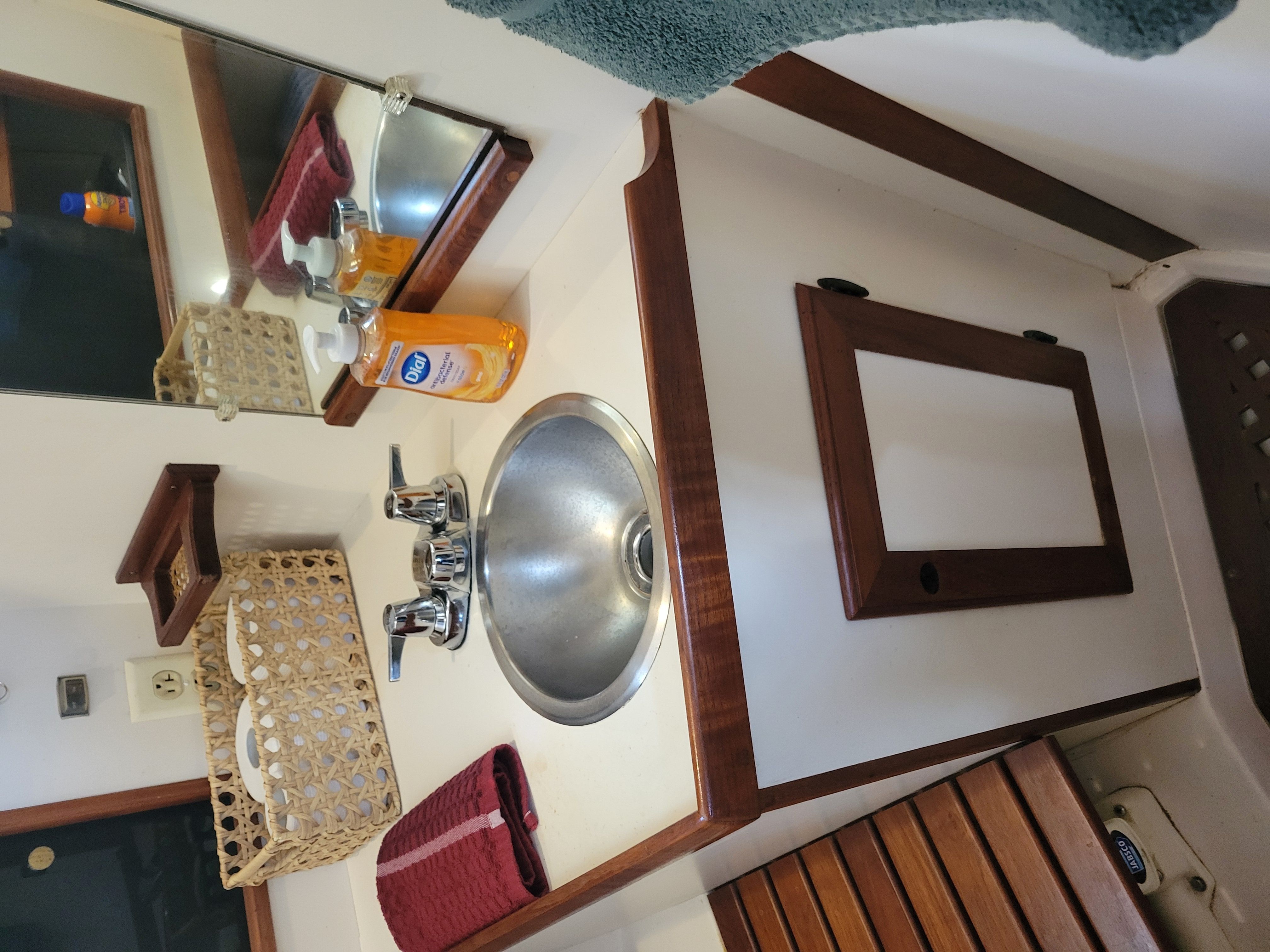 A sink with wooden trim and mirror in a boat bathroom.
