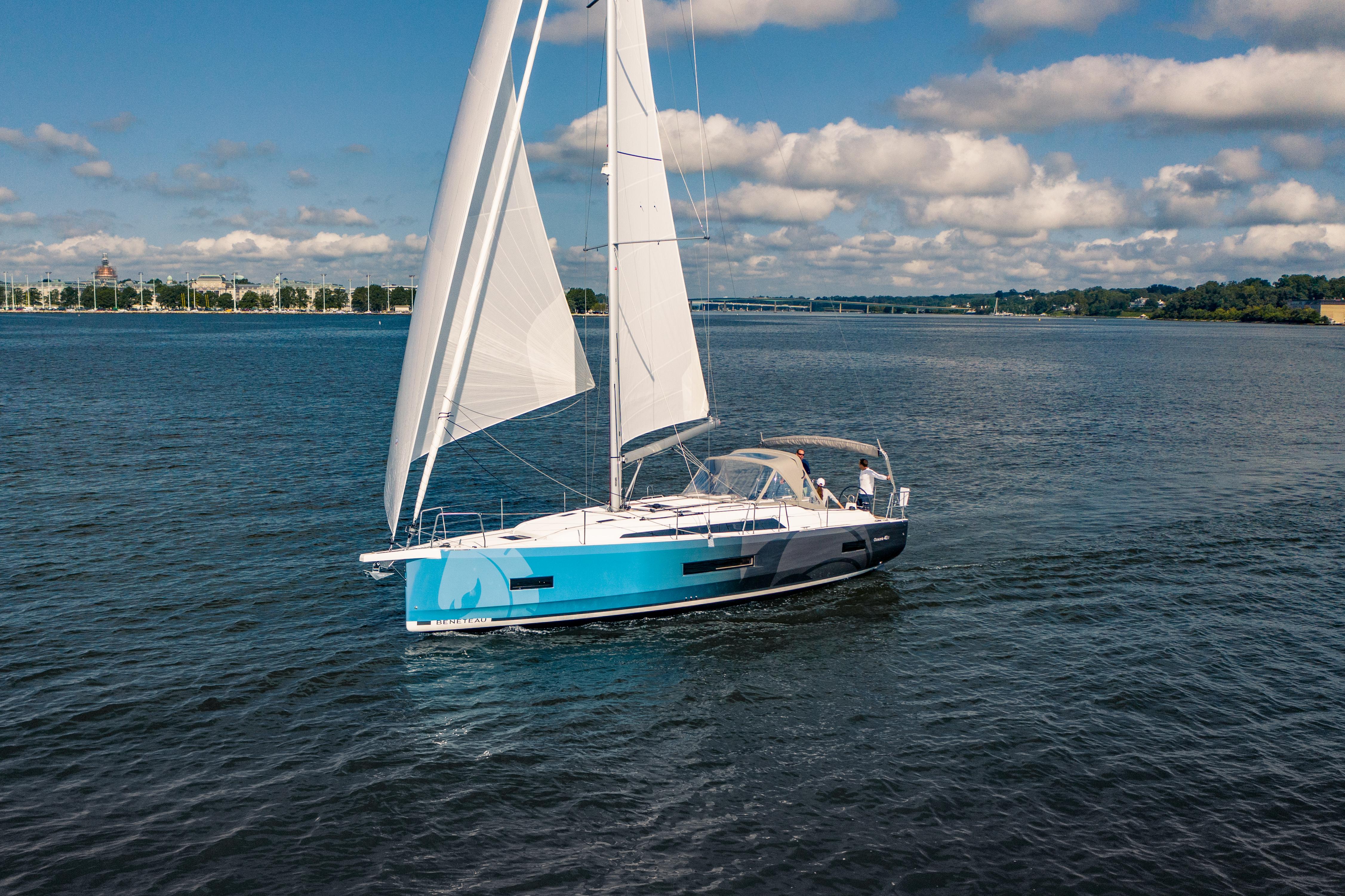 2025 Beneteau Oceanis 40.1 sailing on a calm lake under a partly cloudy sky.