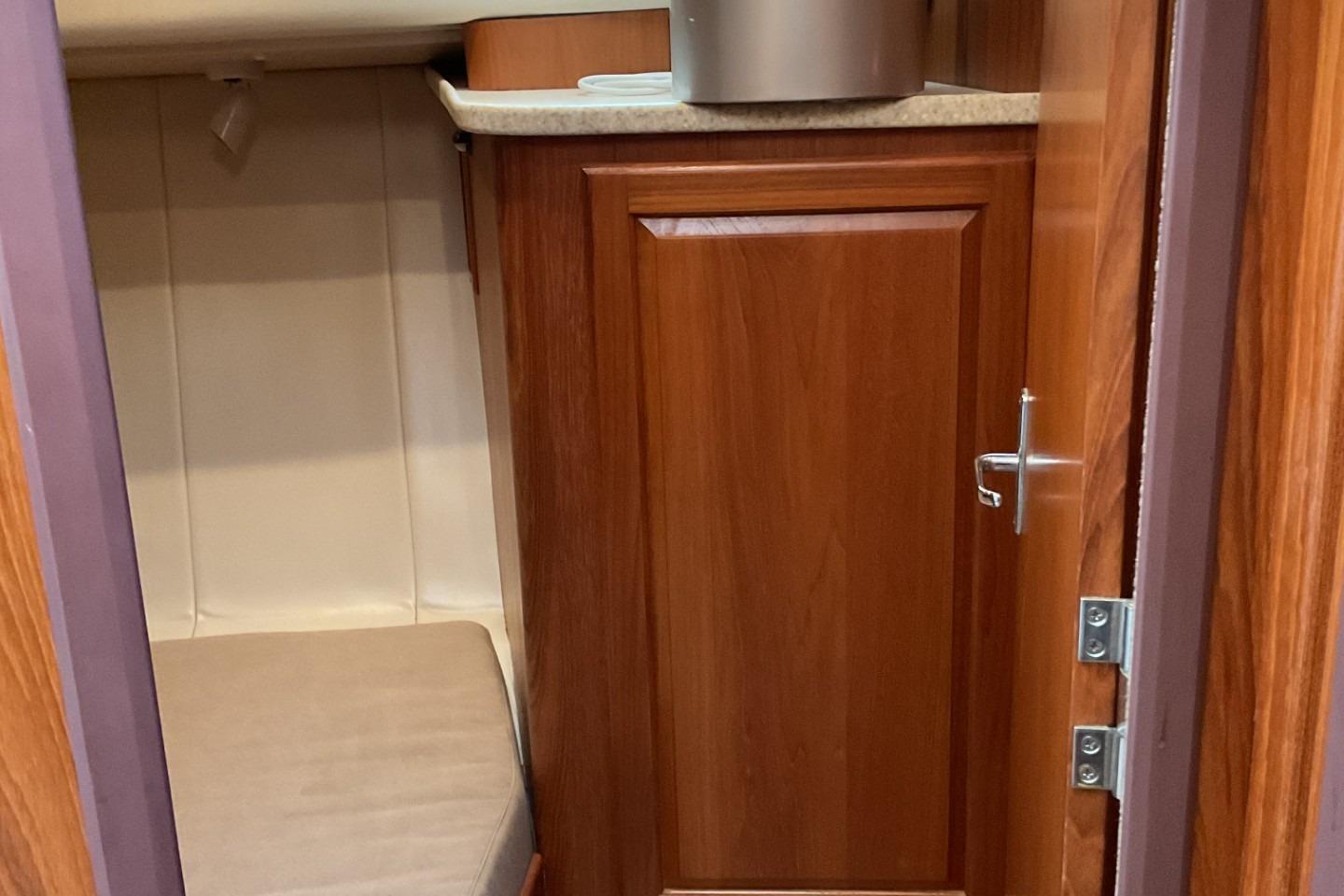1999 Mainship 350 Trawler interior with wooden cabinetry and a small seating area.