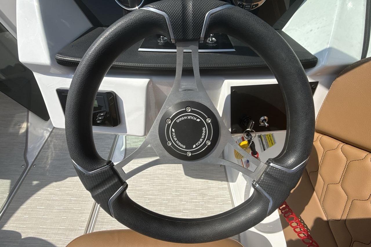 Steering wheel of 2024 Four Winns H1 OB boat with modern design and controls.