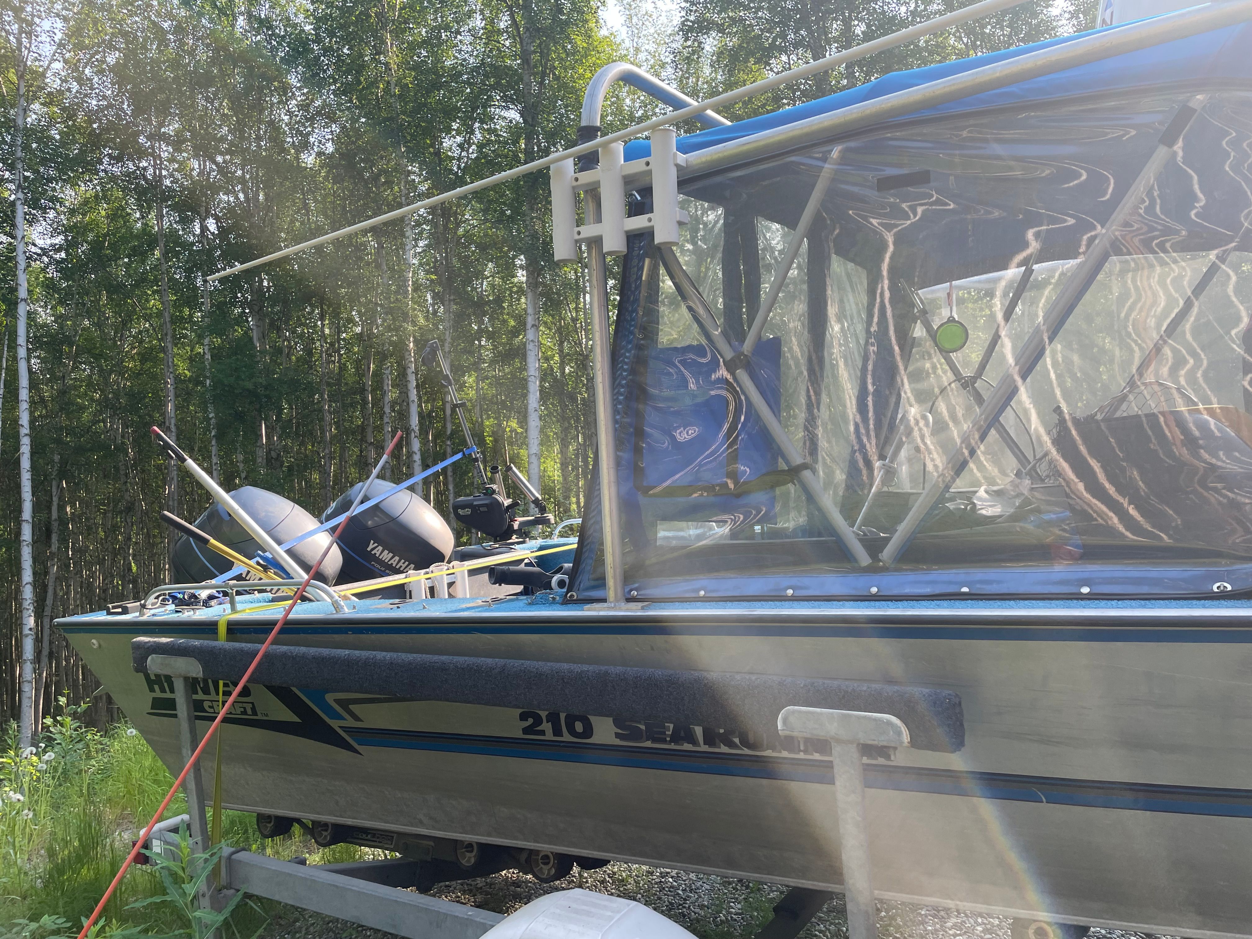 A 1998 Hewescraft Sea Runner 210 boat on a trailer in a wooded area.