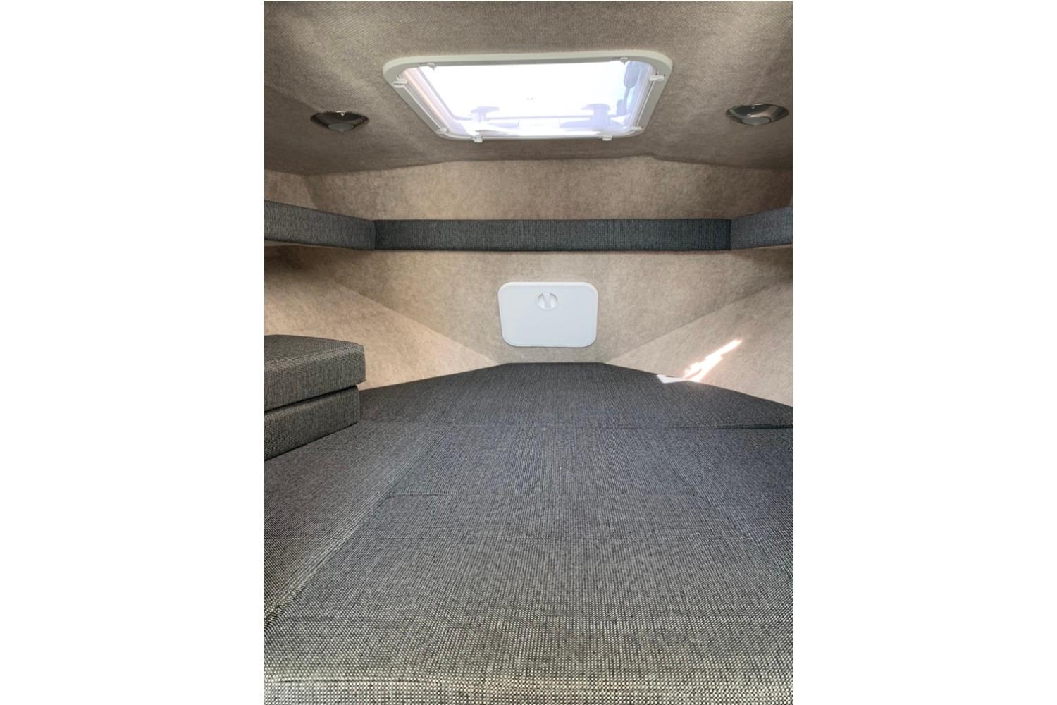 Interior cabin of 2026 Sea Sport Kenai 2600 boat, featuring gray upholstery and overhead hatch.