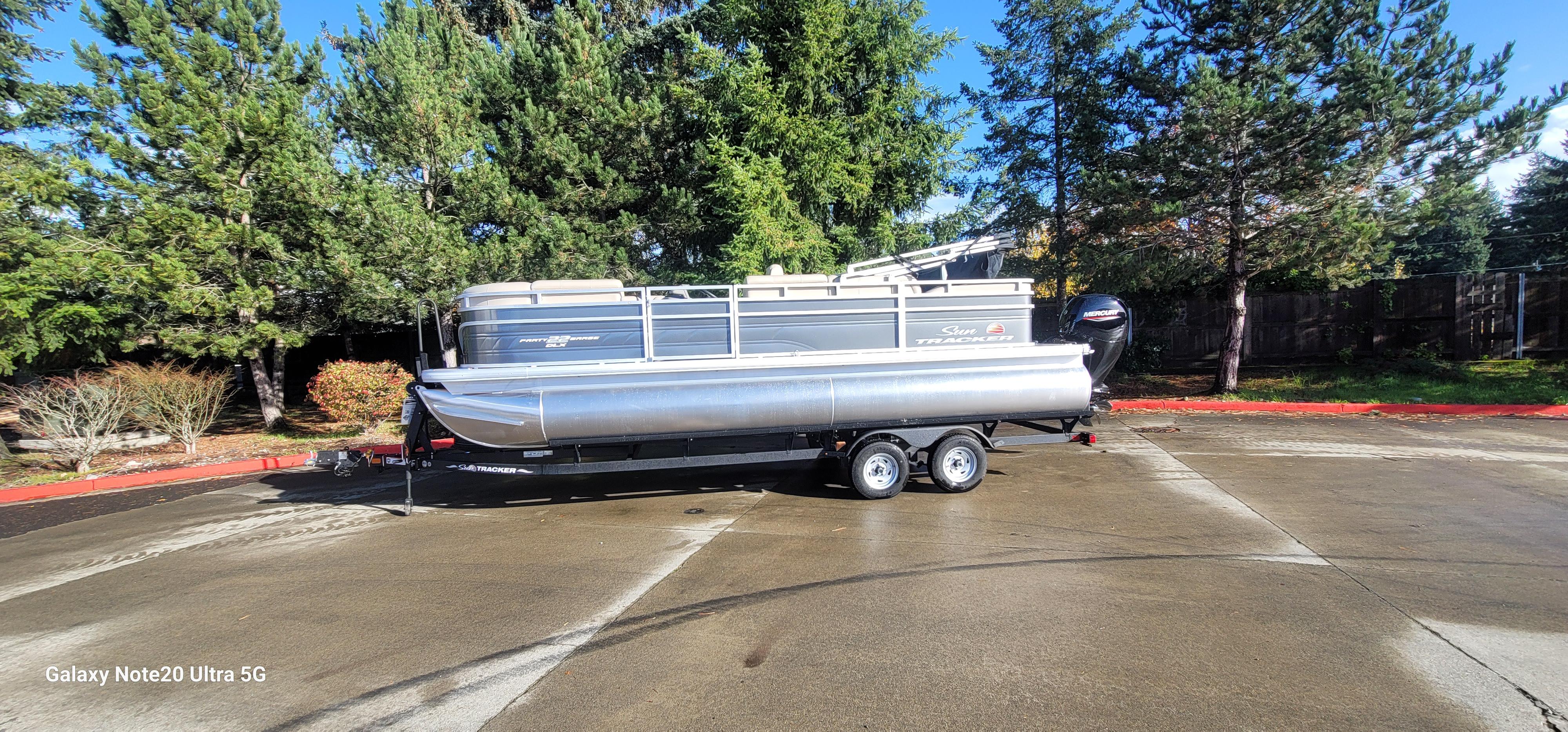 2025 Sun Tracker Party Barge 22 RF DLX pontoon boat on trailer, parked outdoors.