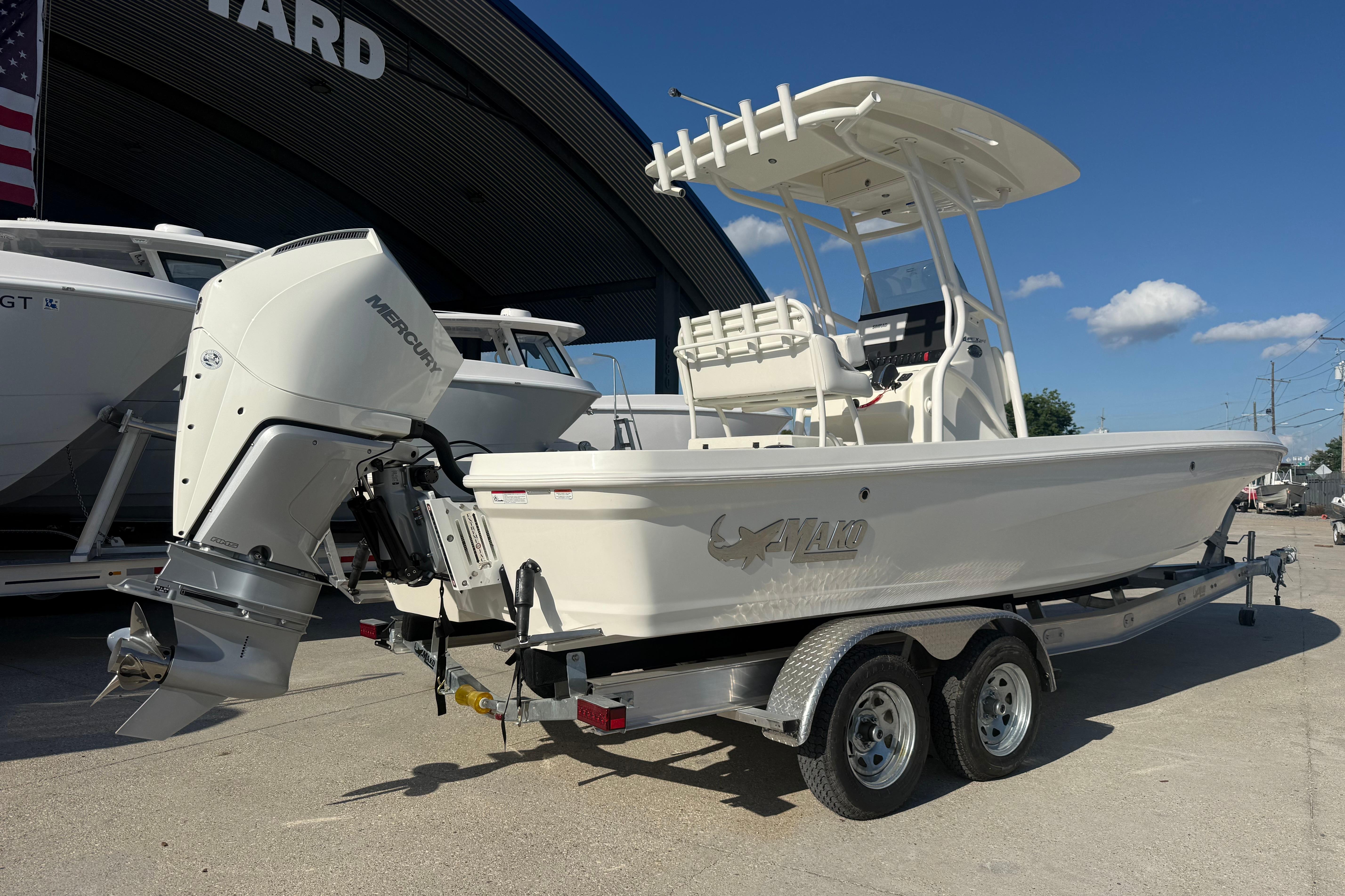 2026 Mako 24 APEX boat on trailer, featuring Mercury outboard motor, parked outdoors.