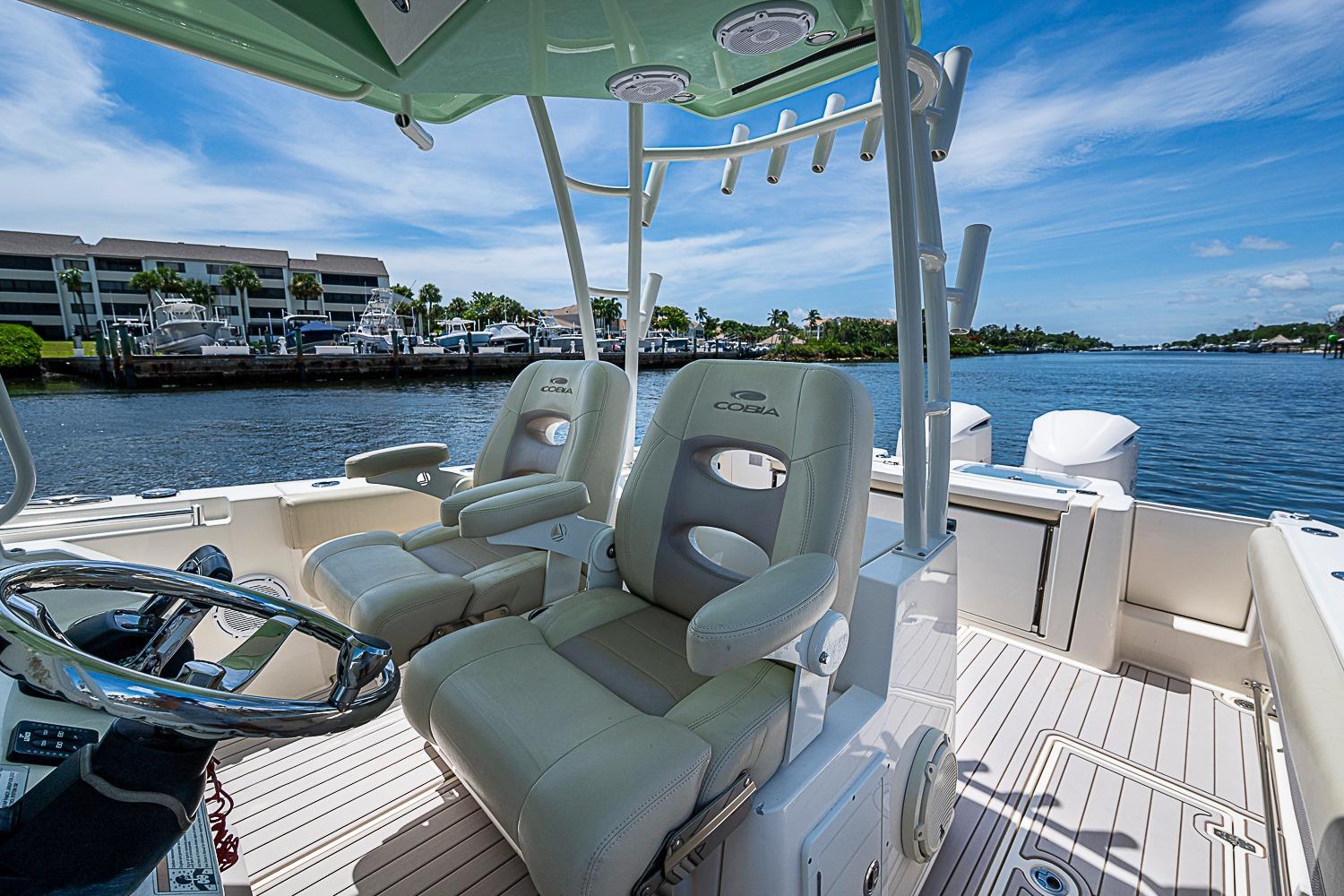 2019 Cobia 320 Center Console boat interior with helm seats and waterfront view.