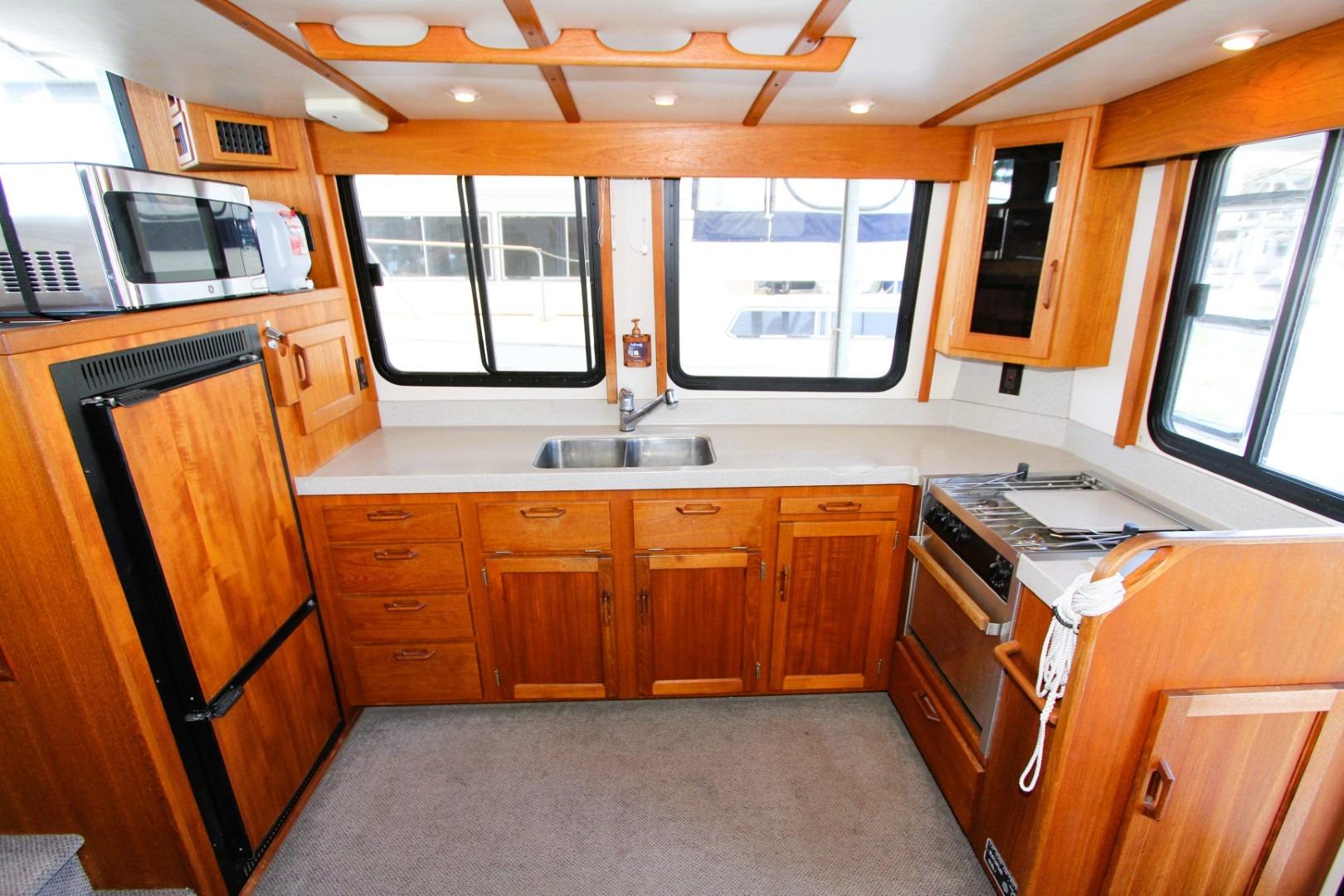 2002 Nordic Tug 37 interior kitchen with wooden cabinetry, stove, and microwave.