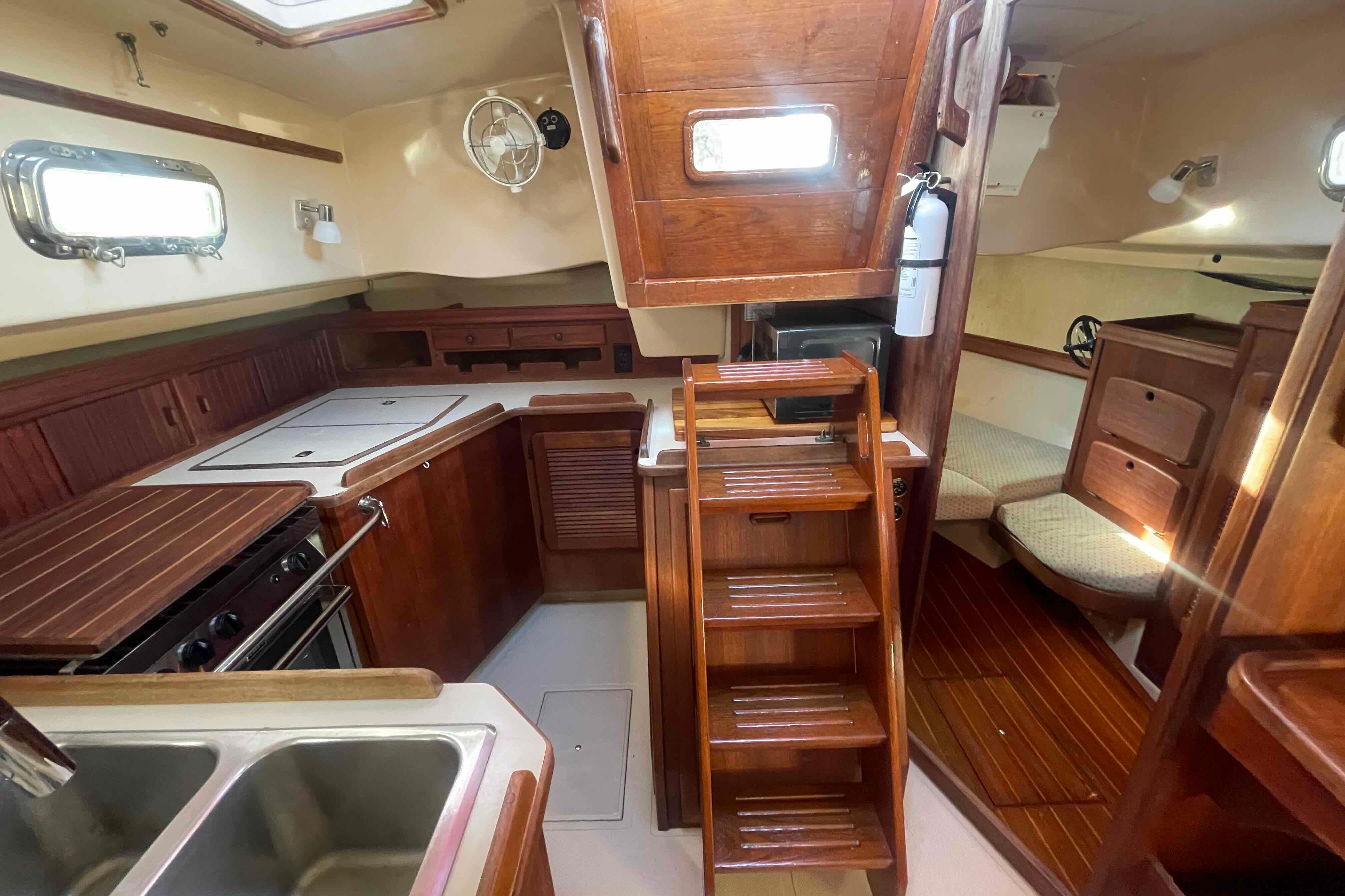 1989 Island Packet 35 yacht interior with wooden cabinetry, kitchen, and seating area.