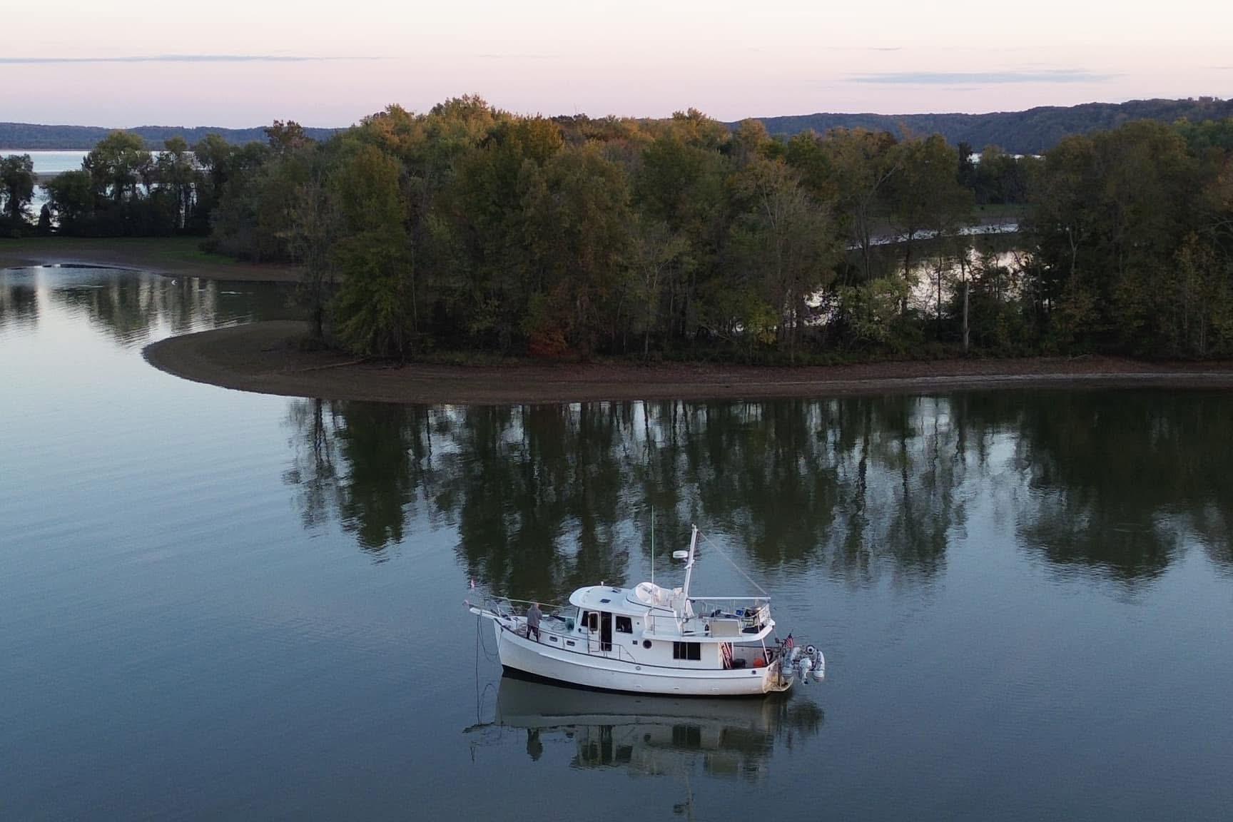 Kadey-Krogen 39 boat from 2001 anchored on a serene lake with lush trees.