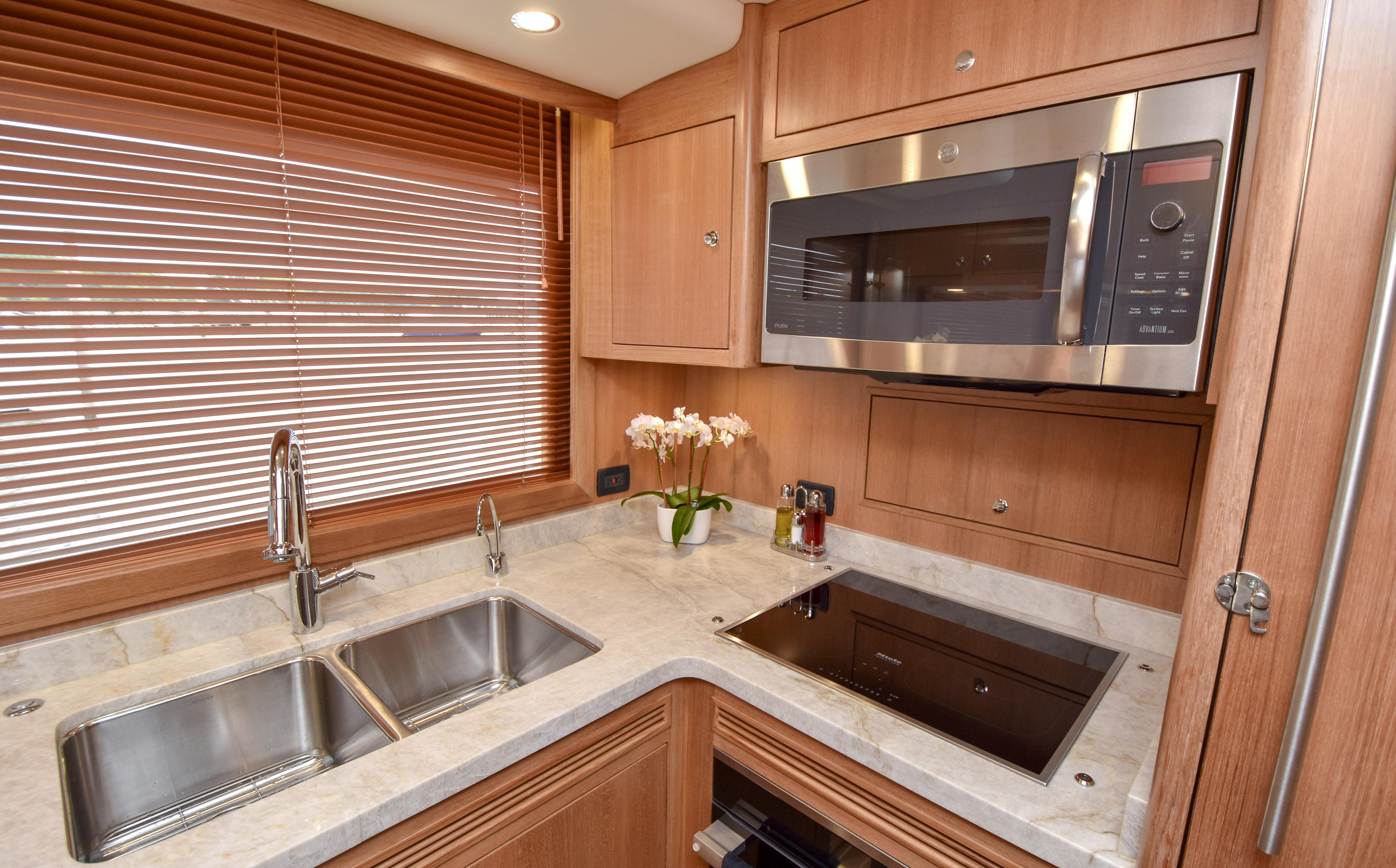 Modern kitchen in 2020 Fleming 78 yacht with stainless steel appliances and wooden cabinetry.