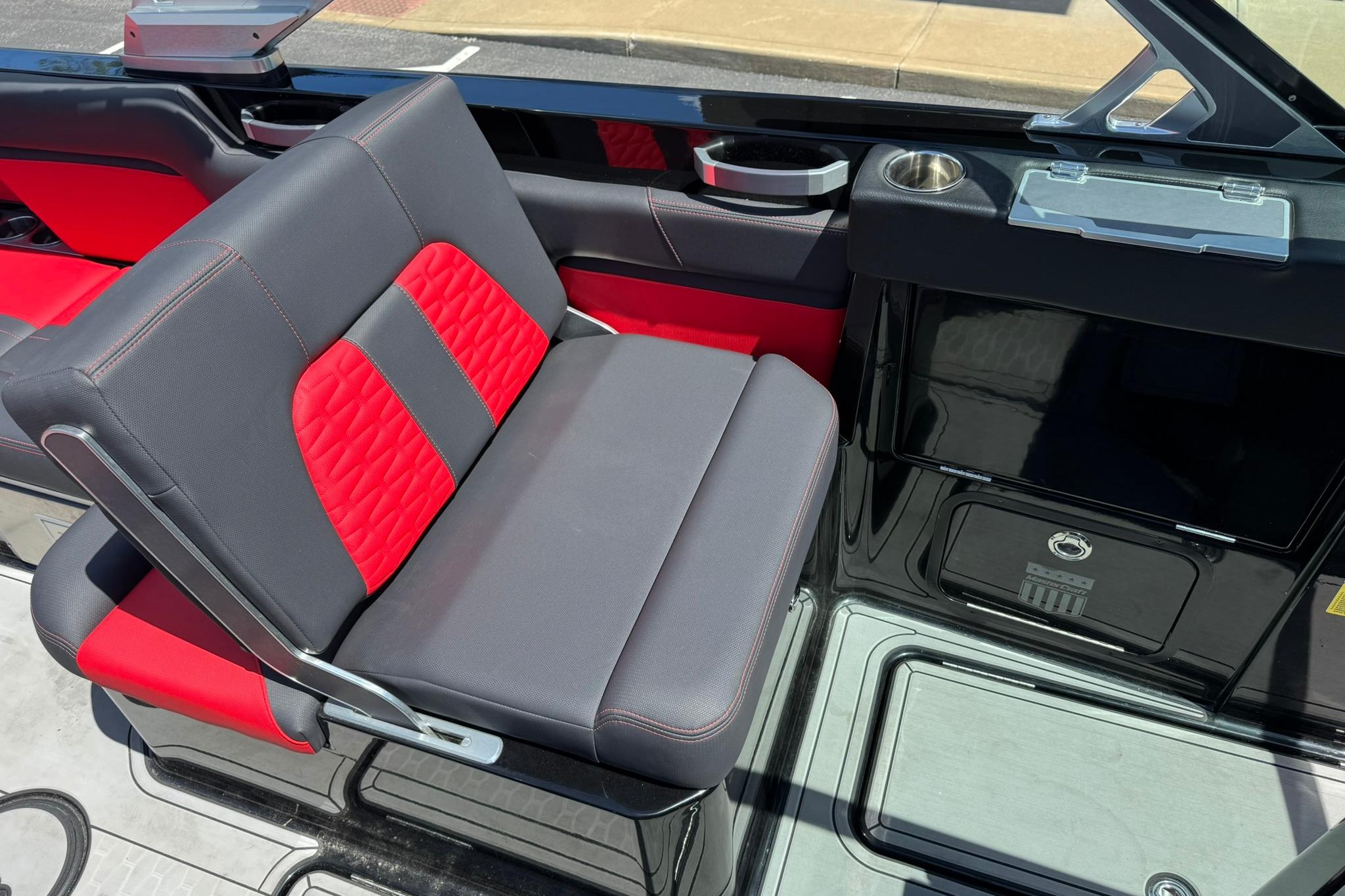 2021 MasterCraft X26 boat interior with red and gray seating, cup holder, and sleek design.