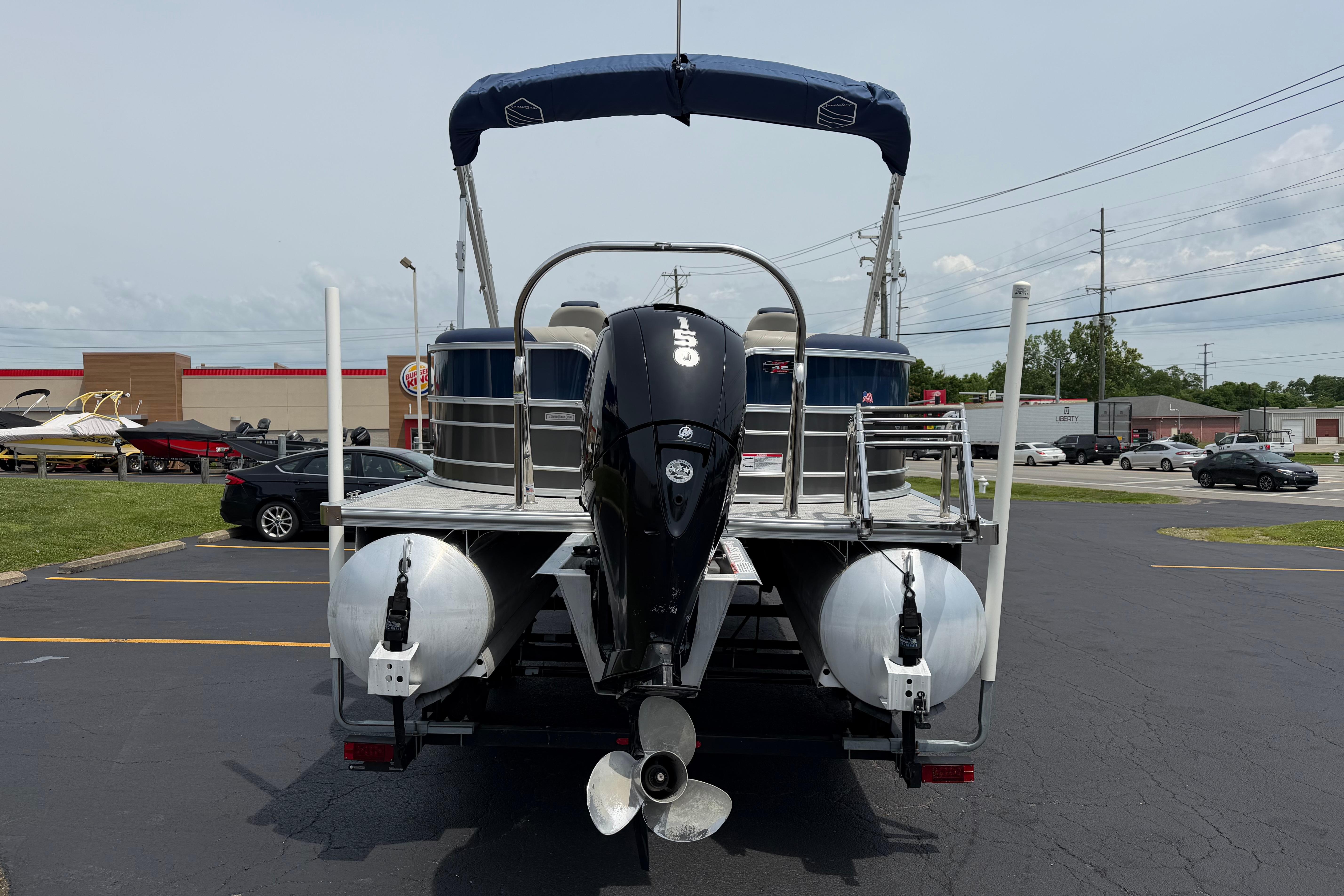 2021 South Bay 224RS LE pontoon boat with outboard motor in parking lot.