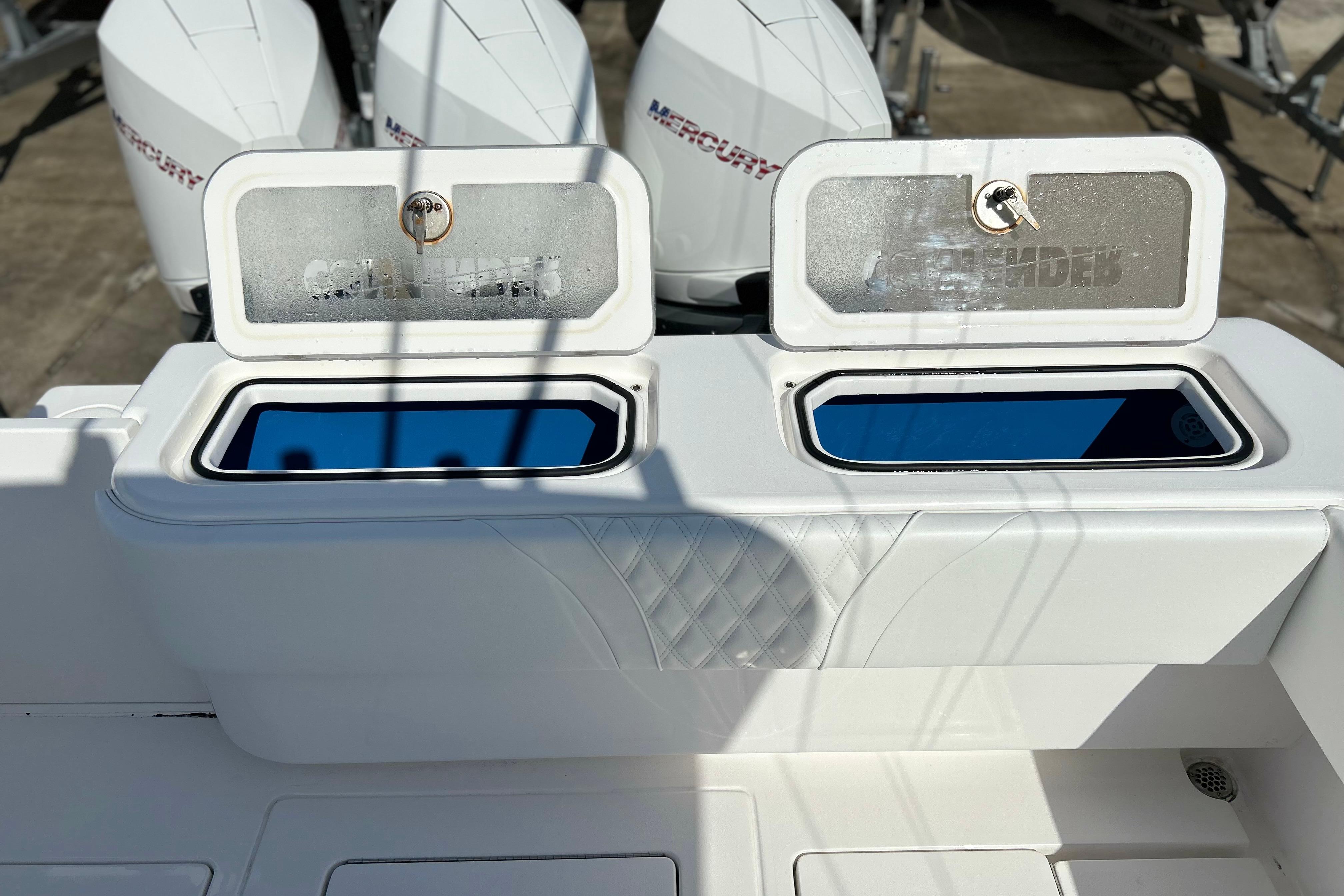 2025 Contender 35 ST boat with open storage compartments and Mercury engines in the background.