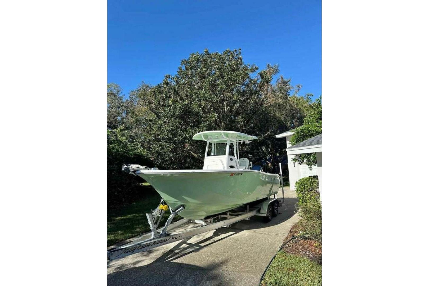 2023 Sea Pro 239 Deep V CC boat on trailer, parked in driveway under clear blue sky.