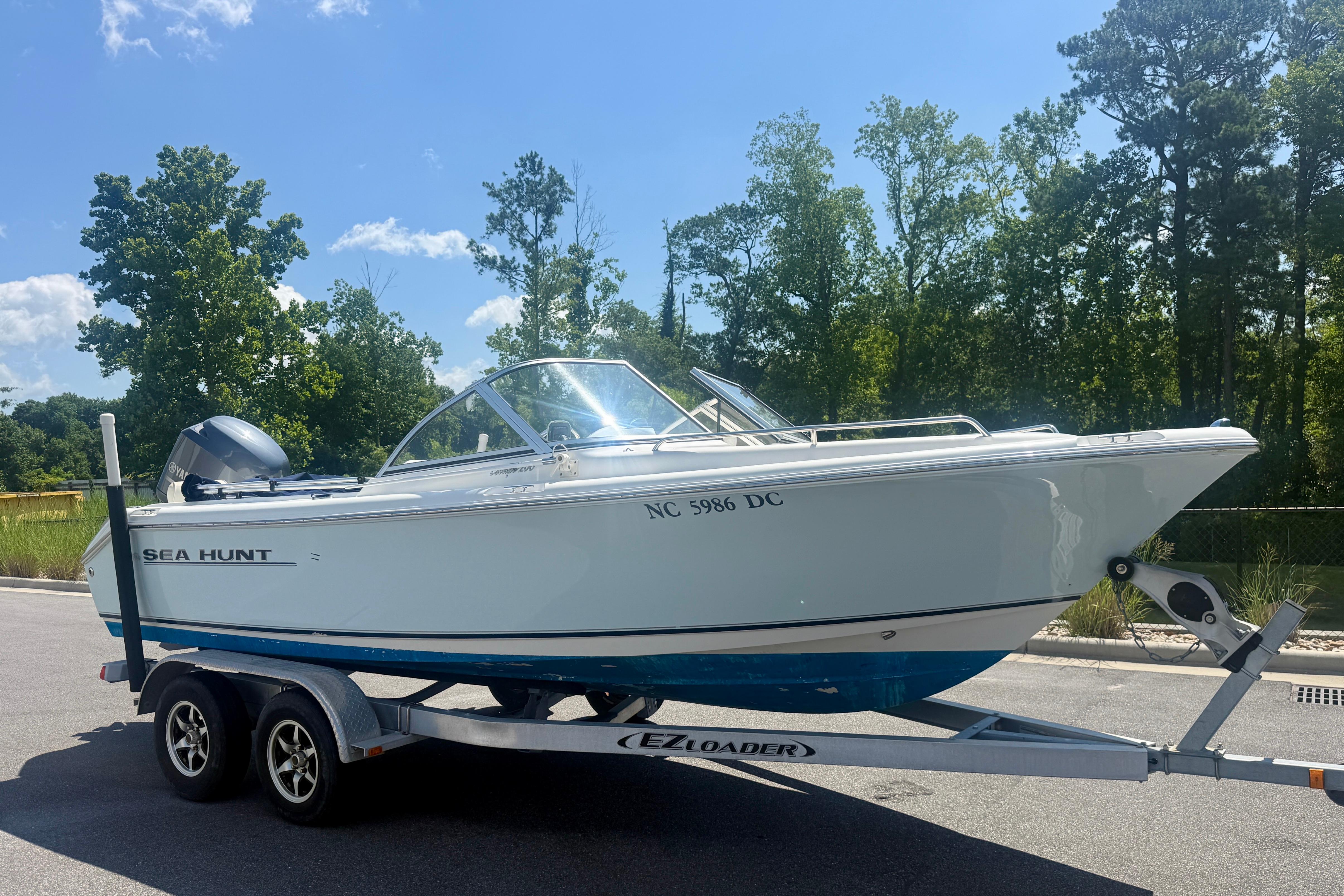 2006 Sea Hunt Escape 200 boat on trailer, parked outdoors with trees in background.
