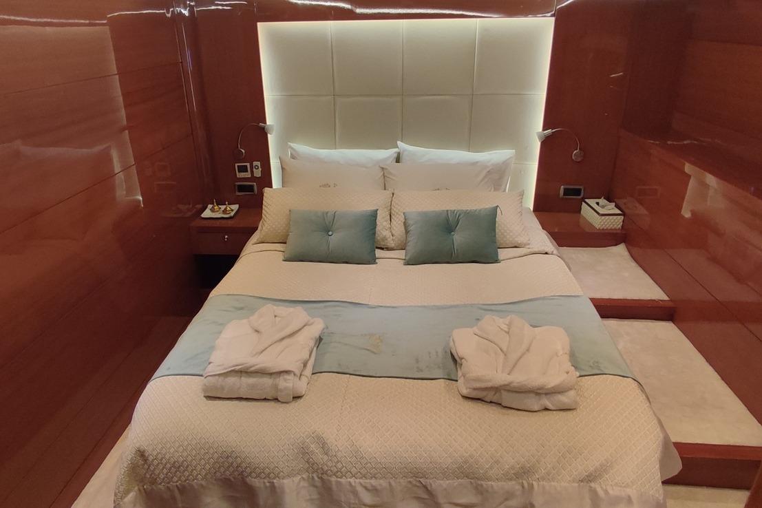 Luxurious bedroom interior on 2009 Aganlar Custom Built Gulet 34M yacht, featuring elegant bedding and wood paneling.