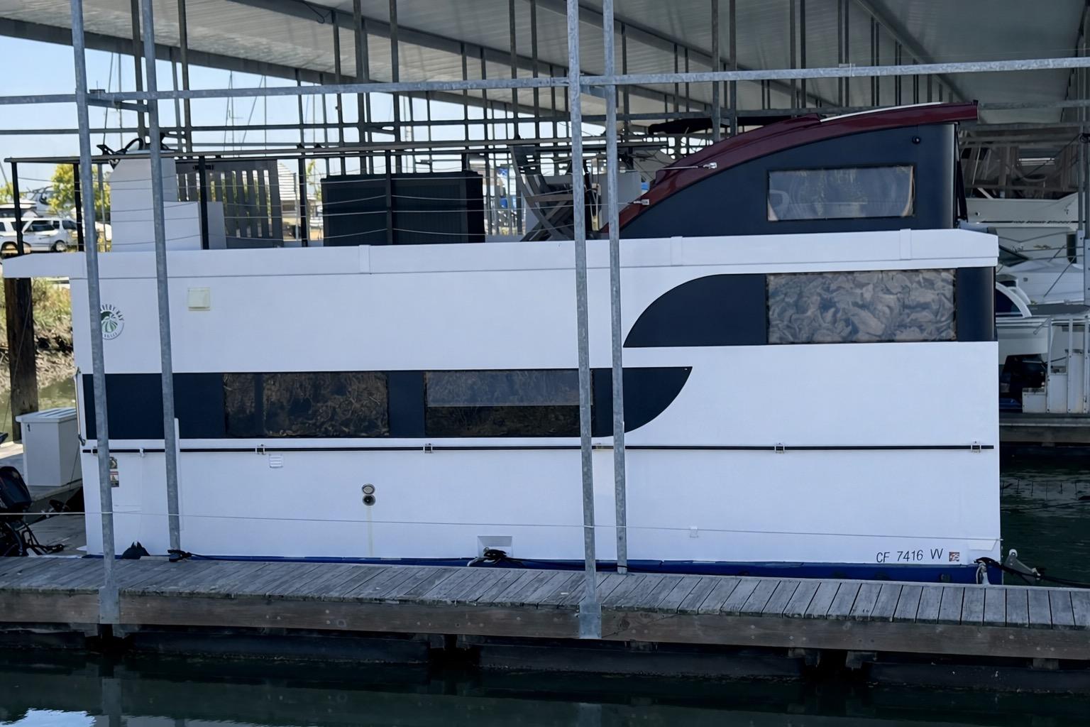 Modern 2022 Navisyo NV.08 houseboat docked in a marina under a covered structure.