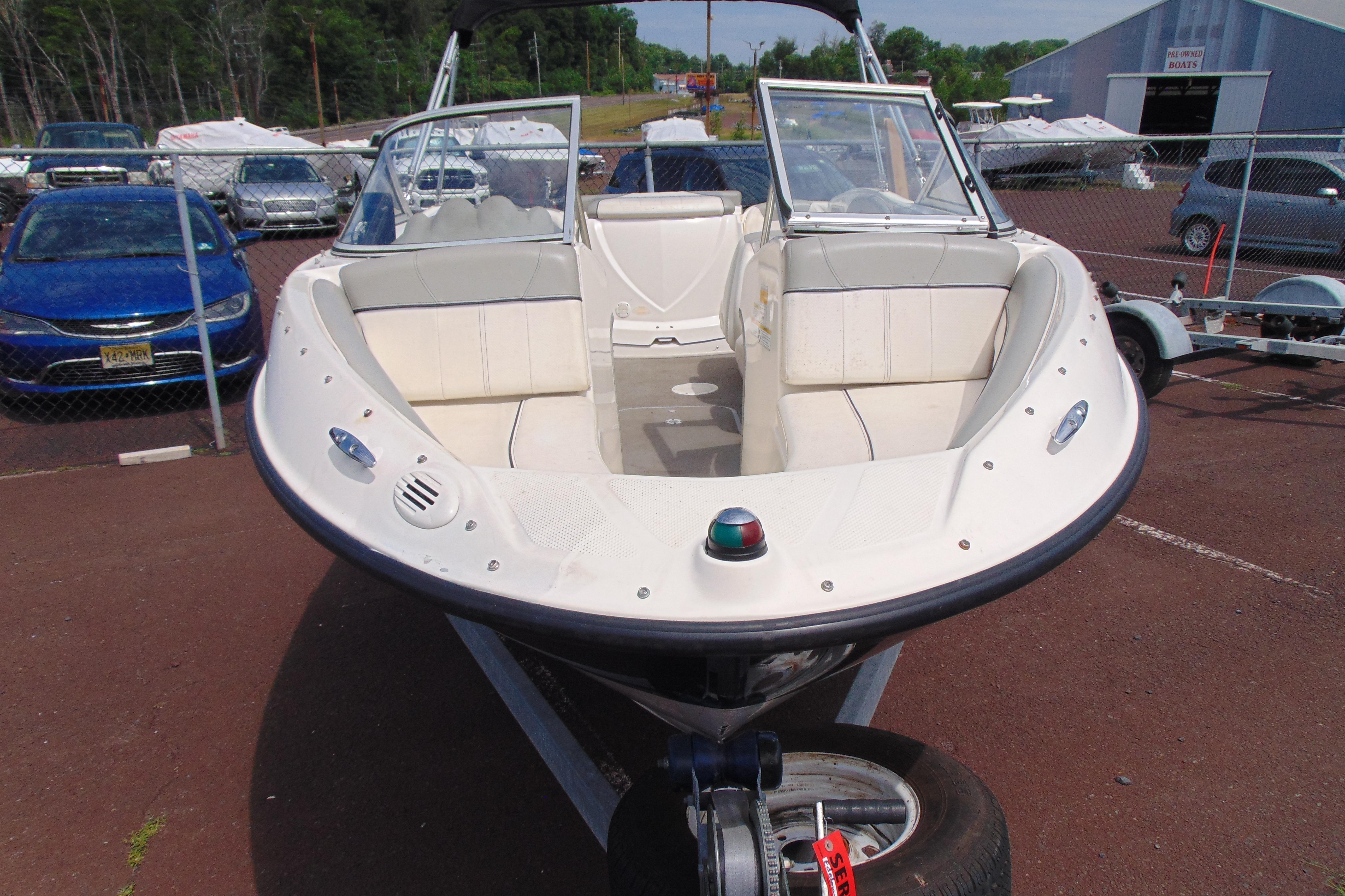 2012 Bayliner 185 Bowrider boat on trailer, parked in a lot with other vehicles.