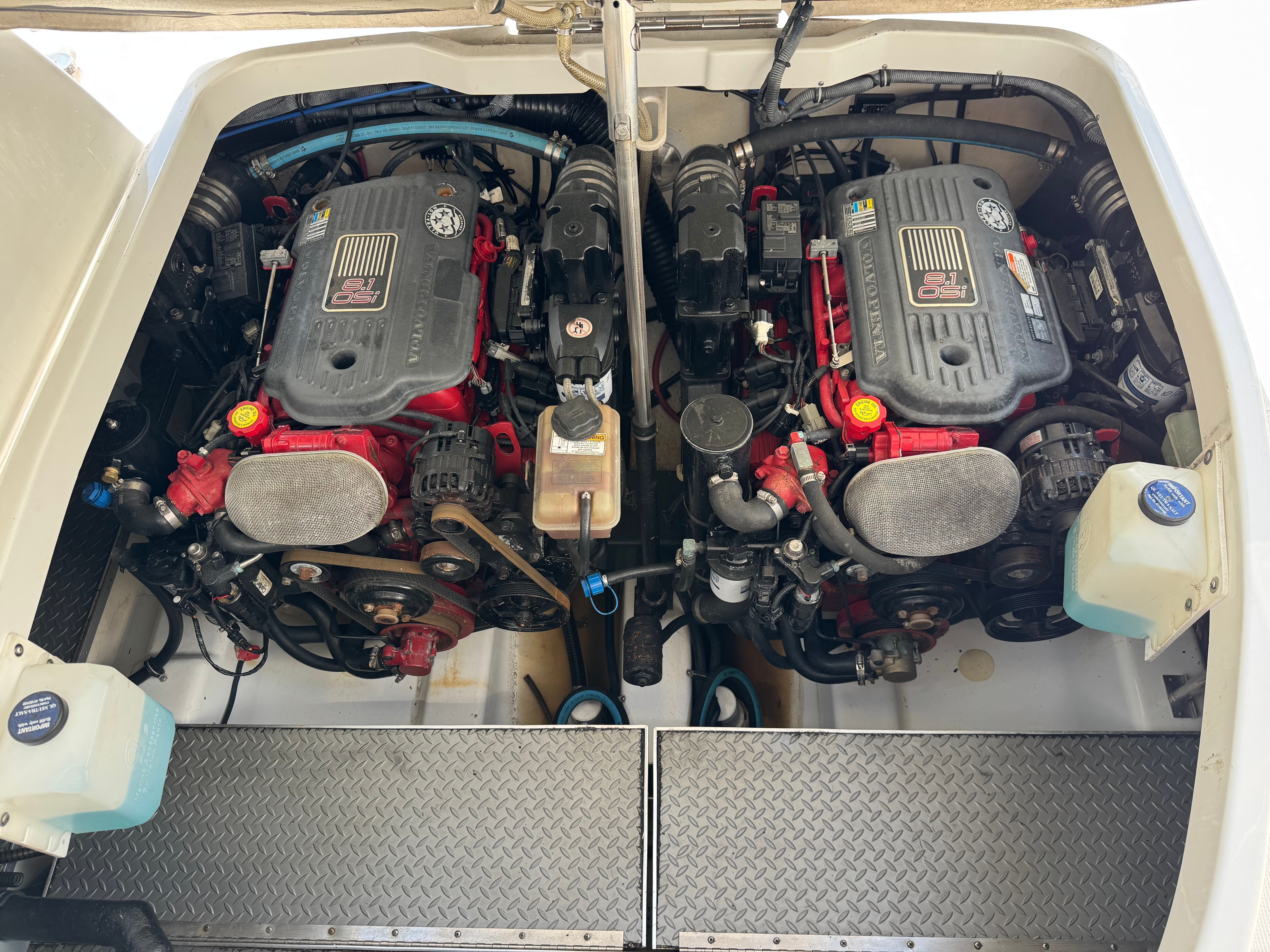 Two engines in a boat's engine compartment with various hoses and components.