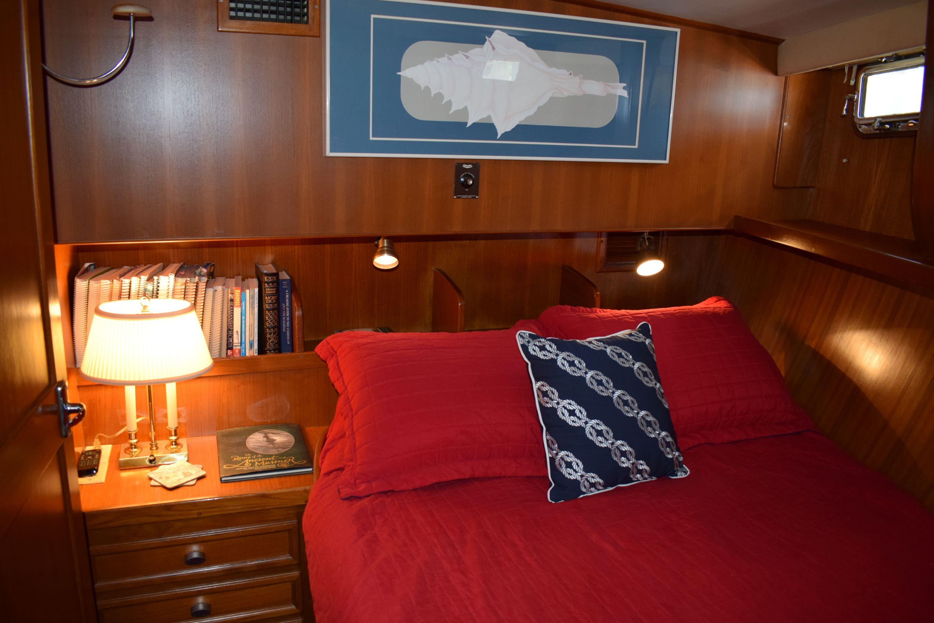 Cozy cabin interior of 1980 Cheoy Lee 52 Motorsailer with red bedding and nautical decor.
