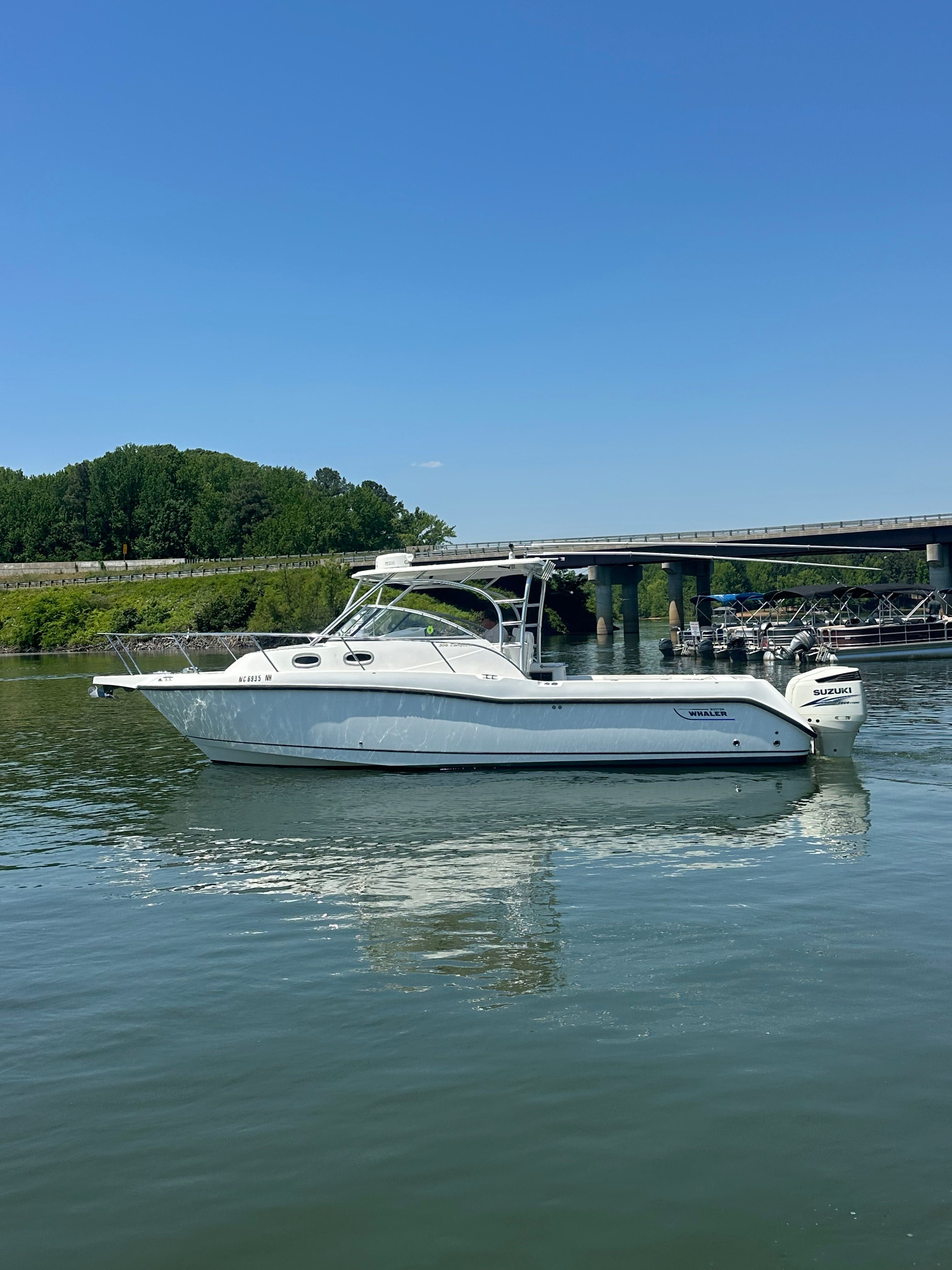 A 2006 Boston Whaler 305 Conquest on calm water near a bridge.