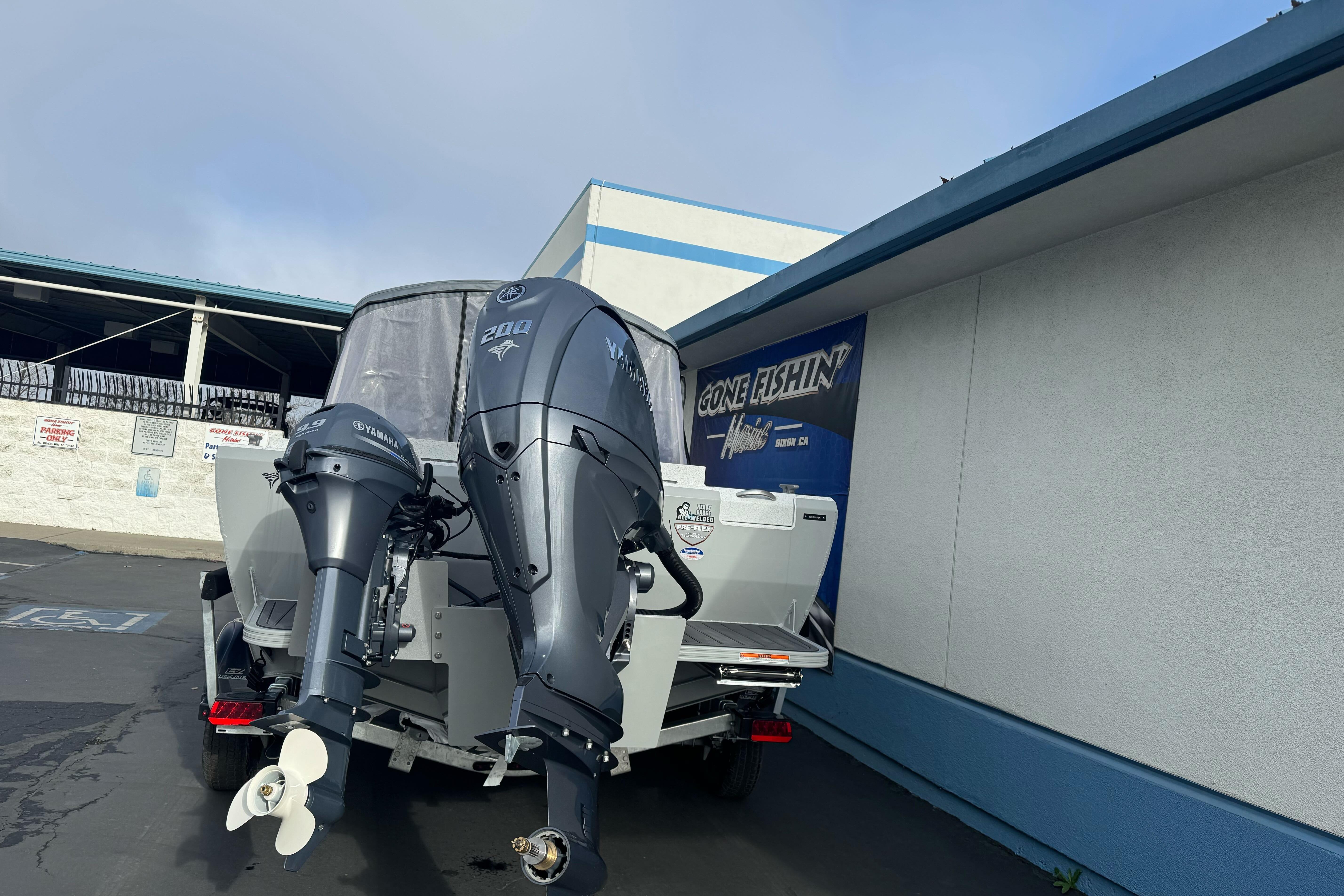 KingFisher 2025 Escape boat with dual Yamaha outboard motors, parked outside a building.